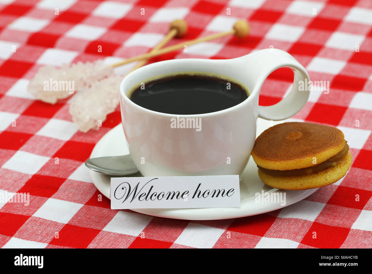 Home Card mit Tasse Kaffee und Japanische Cookie auf kariertem Tuch Willkommen Stockfoto