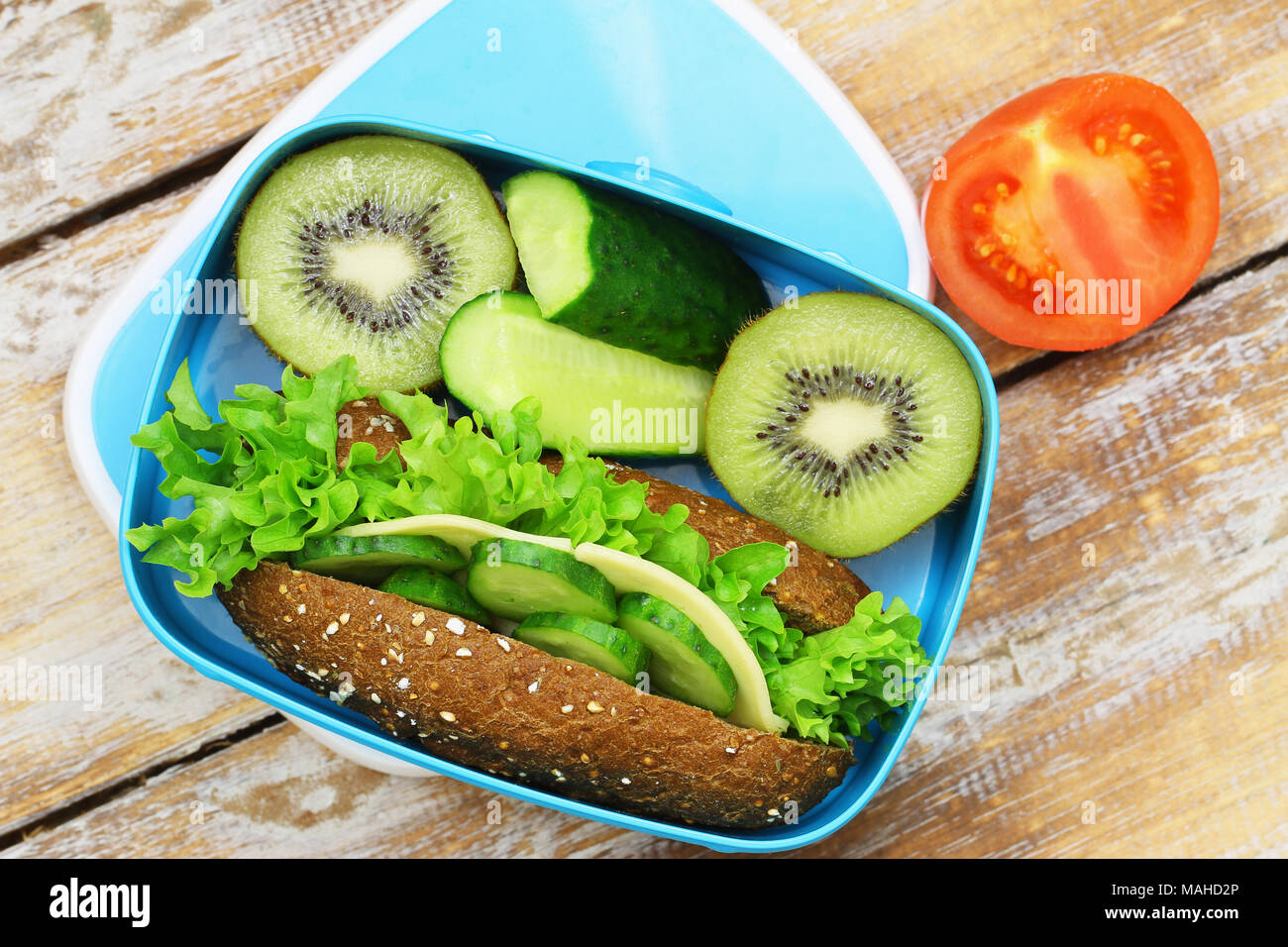 Gesundes Mittagessen Box mit Roggen Cheese Roll, Gurken Sticks und Kiwi Stockfoto