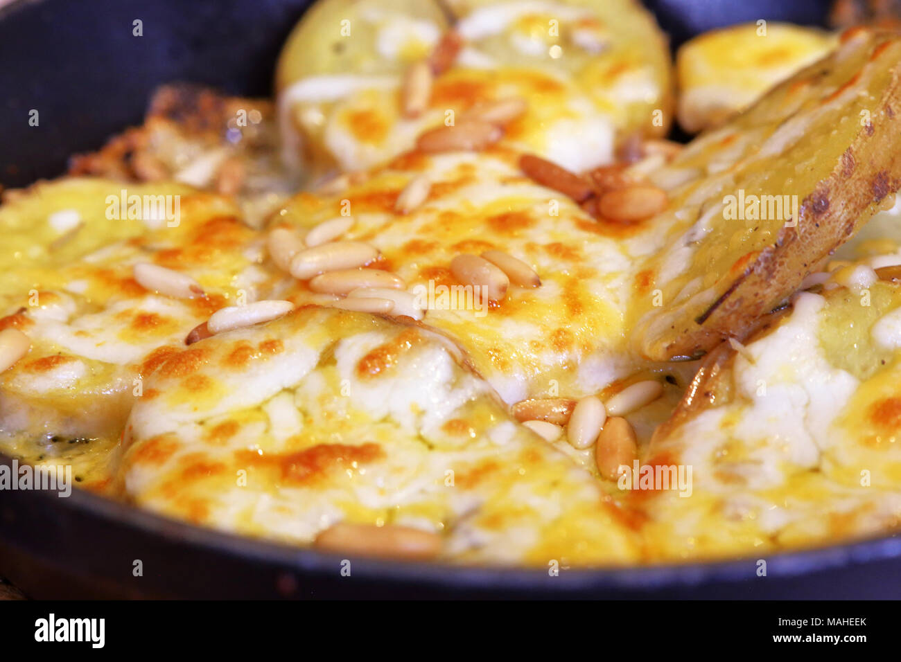 In Scheiben geschnitten gebackene Kartoffeln überbacken mit Käse und Pinienkernen und gegrillt, Stockfoto