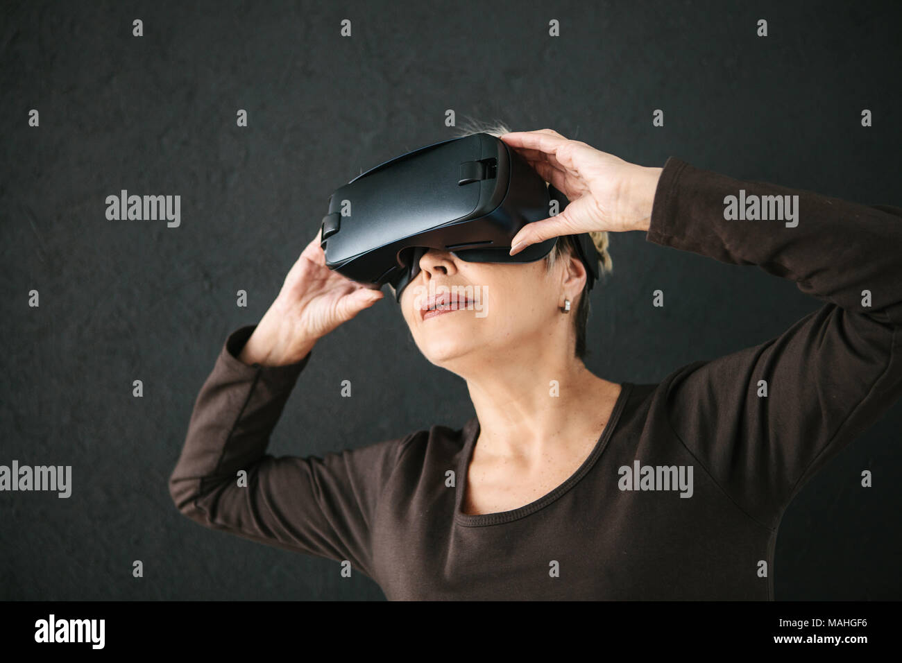 Eine ältere Frau in der virtuellen Realität Gläser. Eine ältere Person mit moderner Technologie Stockfoto