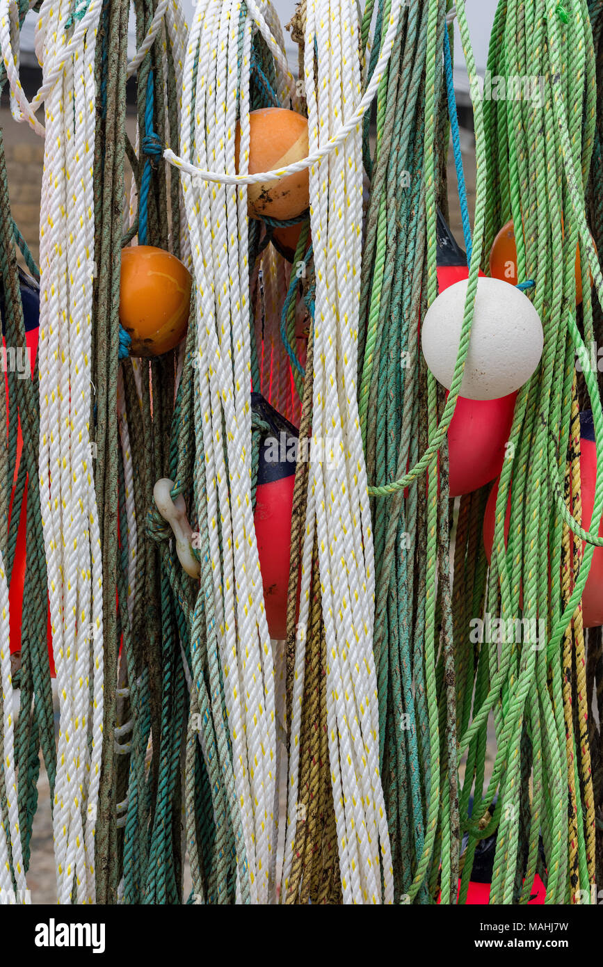 Eine Auswahl oder Mischung Vielfalt der alten Fischerdorf Seile, Drähte und bunten maritimen und nautischen Angeln schwebt und Bojen hängen in einem Hafen. Stockfoto