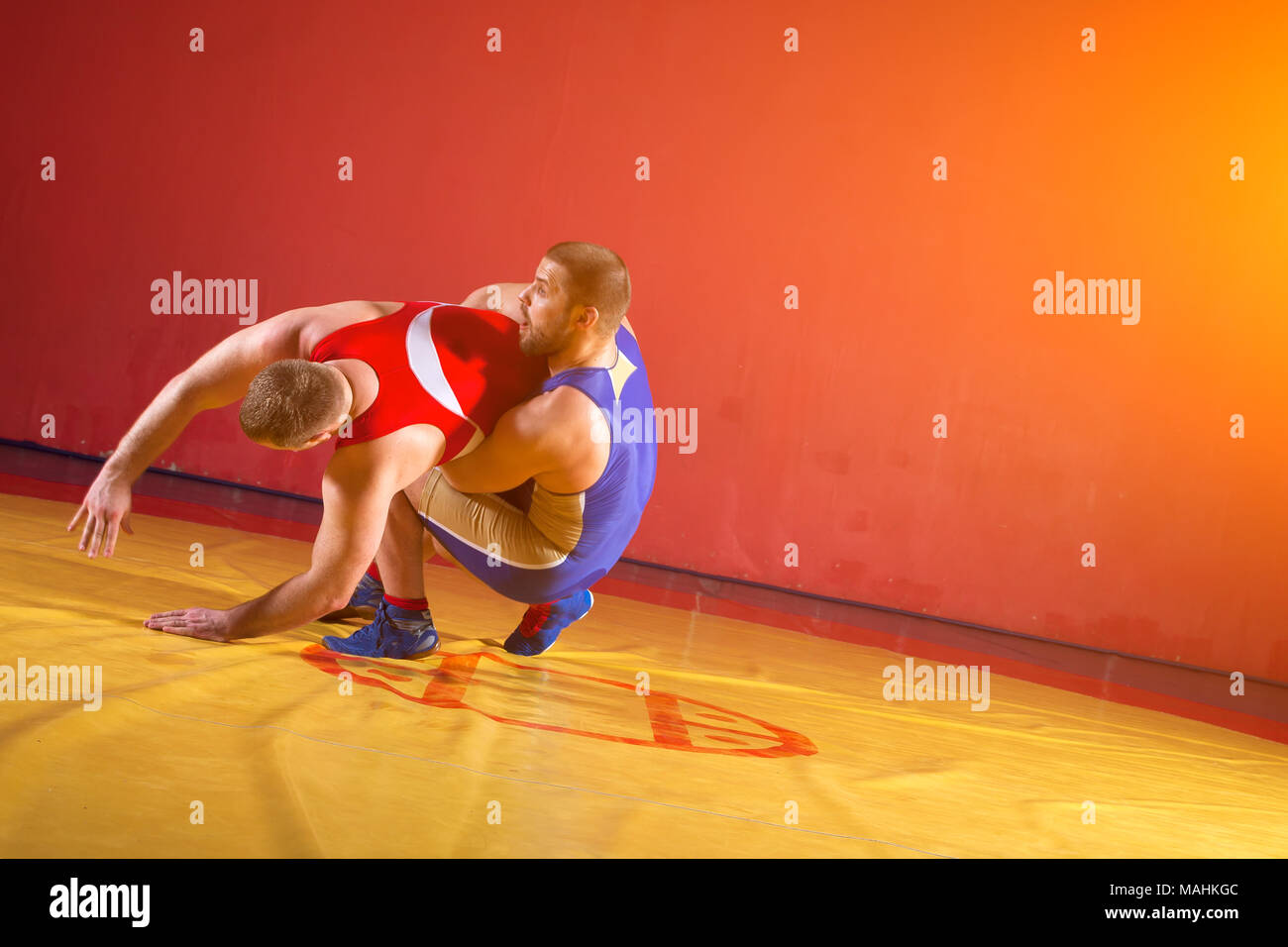 Zwei junge Mann Ringkämpfer in roten und blauen Uniform wrestling auf einem gelben wrestling Teppich in der Turnhalle. Grappling. Stockfoto