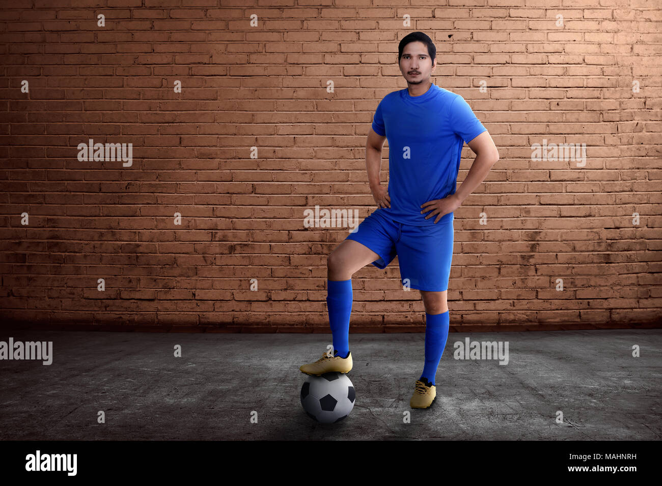 Jungen asiatischen Fußball-Spieler mit Ball auf seine Füße mit Wand Hintergrund Stockfoto