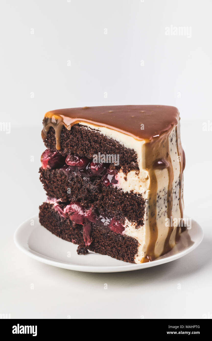 Nahaufnahme von Sweet cherry - Schokoladenkuchen mit Karamell auf Platte isoliert auf weißem Stockfoto