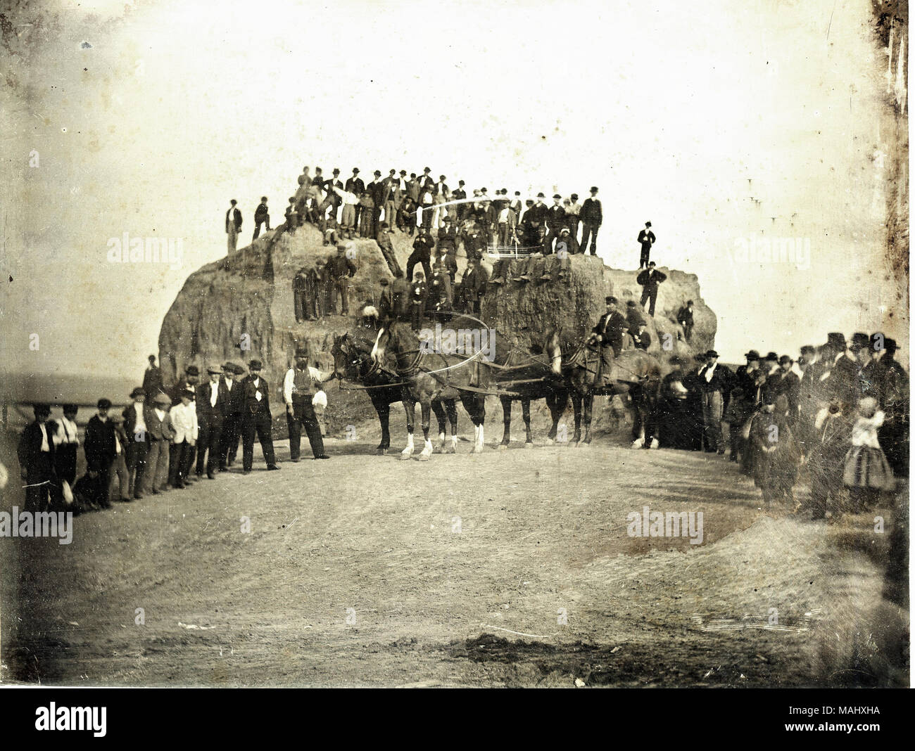 Eine Menge Männer, Kinder, und ein paar Pferde, stand auf und vor dem großen Damm, der gezeigt wird, ist teilweise gestaffelt. Titel: Große erdhügel dargestellt teilweise gestaffelt. . 1869. Thomas M. östlich Stockfoto