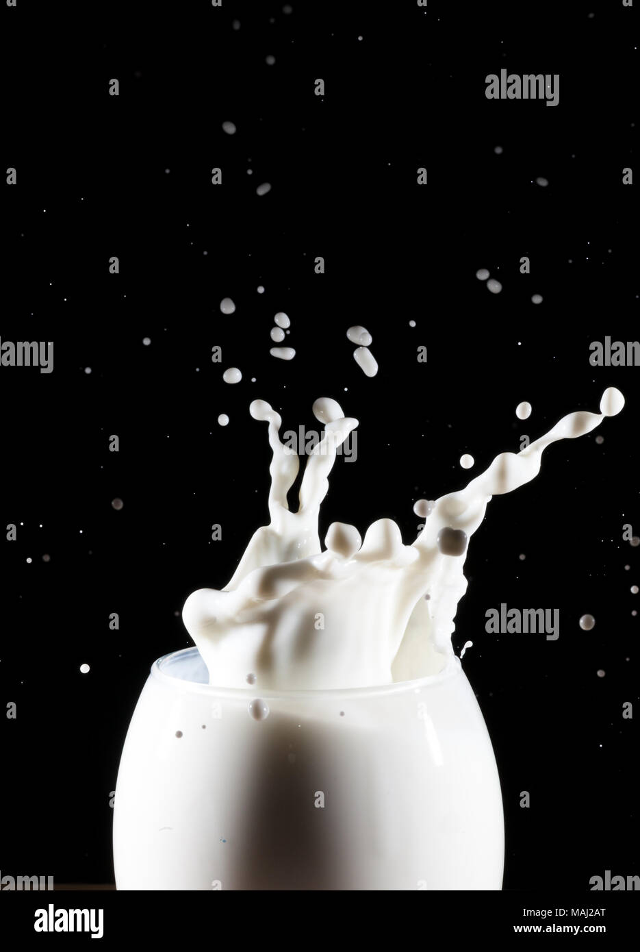 Milch/weiße Flüssigkeit splash aus Glas auf schwarzem Hintergrund Stockfoto