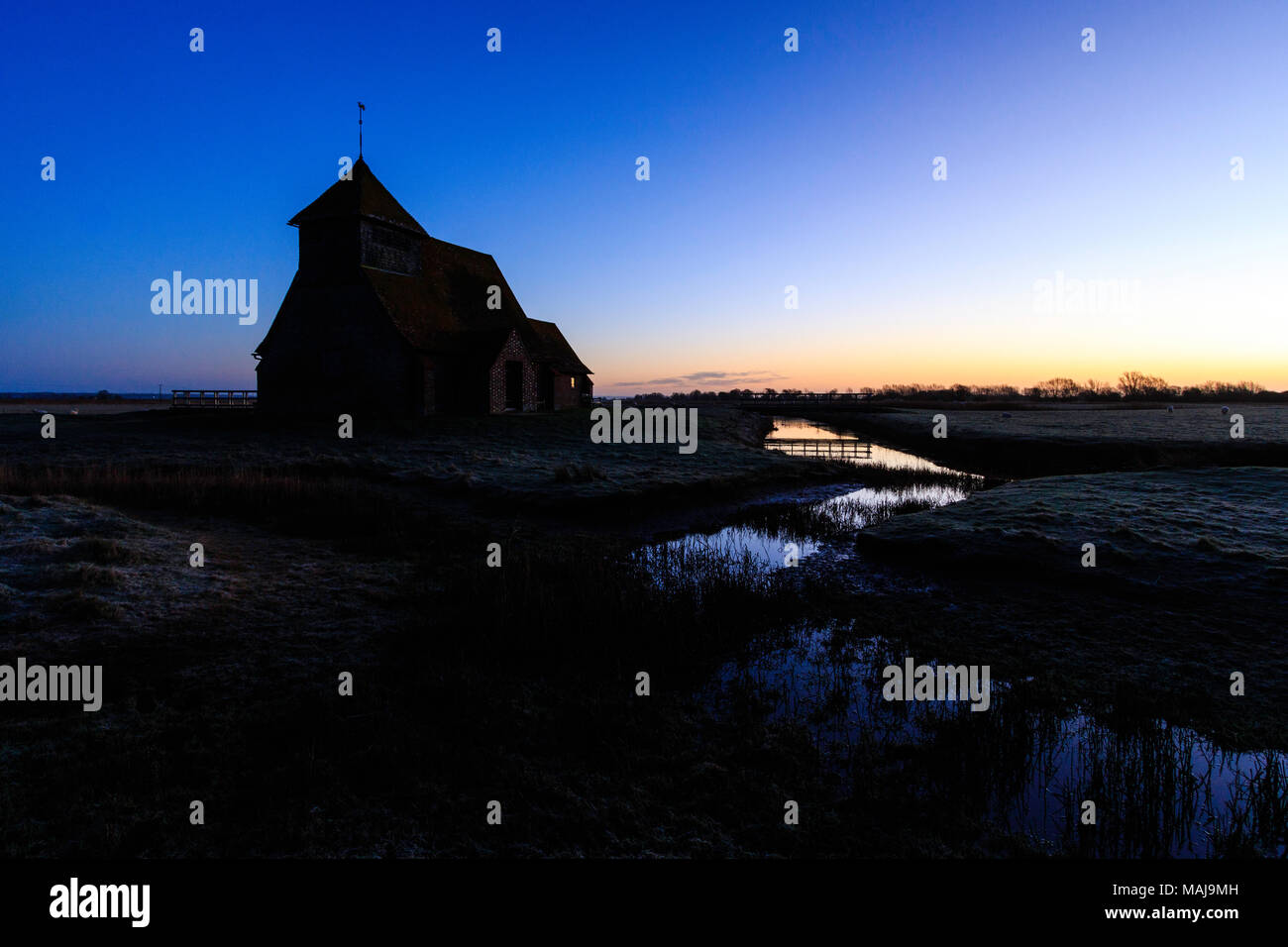 England, Kent, Fairfield. Der hl. Thomas Becket Kirche auf Romney Marsh Silhouette gegen den dunklen Himmel mit dünnen Band von Orange am Horizont. Stockfoto