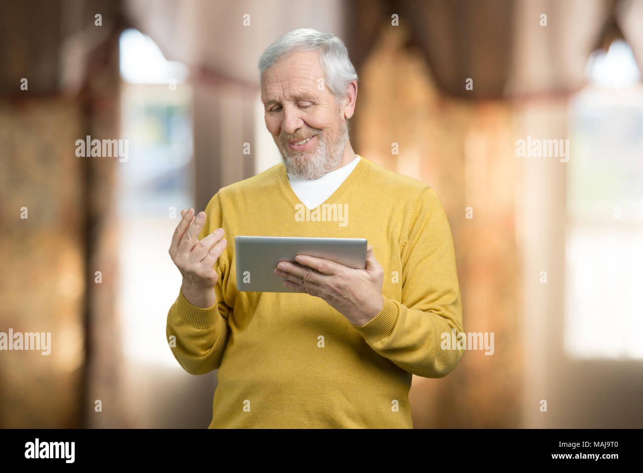 Porträt der alte Mann nutzt digitale Tablet. Senior Großvater surfen auf Tablet im Hause. Unscharfer Hintergrund. Stockfoto