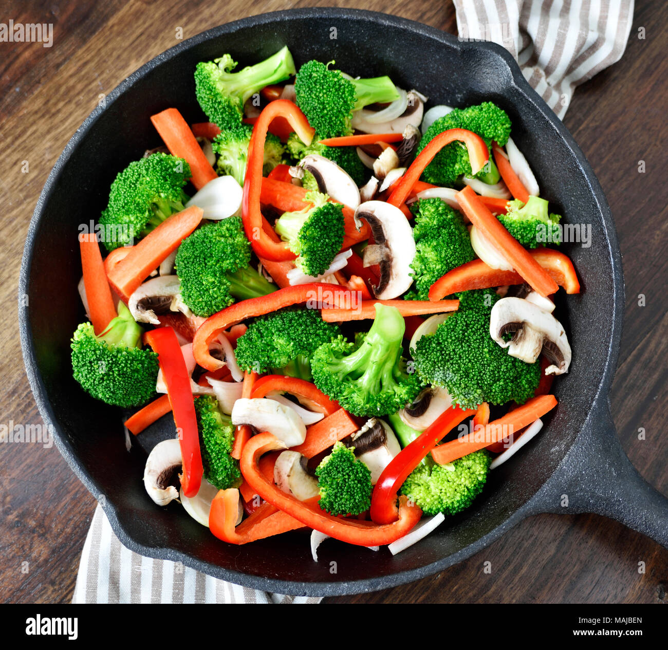 Gesunde Ernährung mit Gemüse in eine eiserne Pfanne oder Topf kochen. Brokkoli, rote Paprika, Möhren und Champignons. Stockfoto