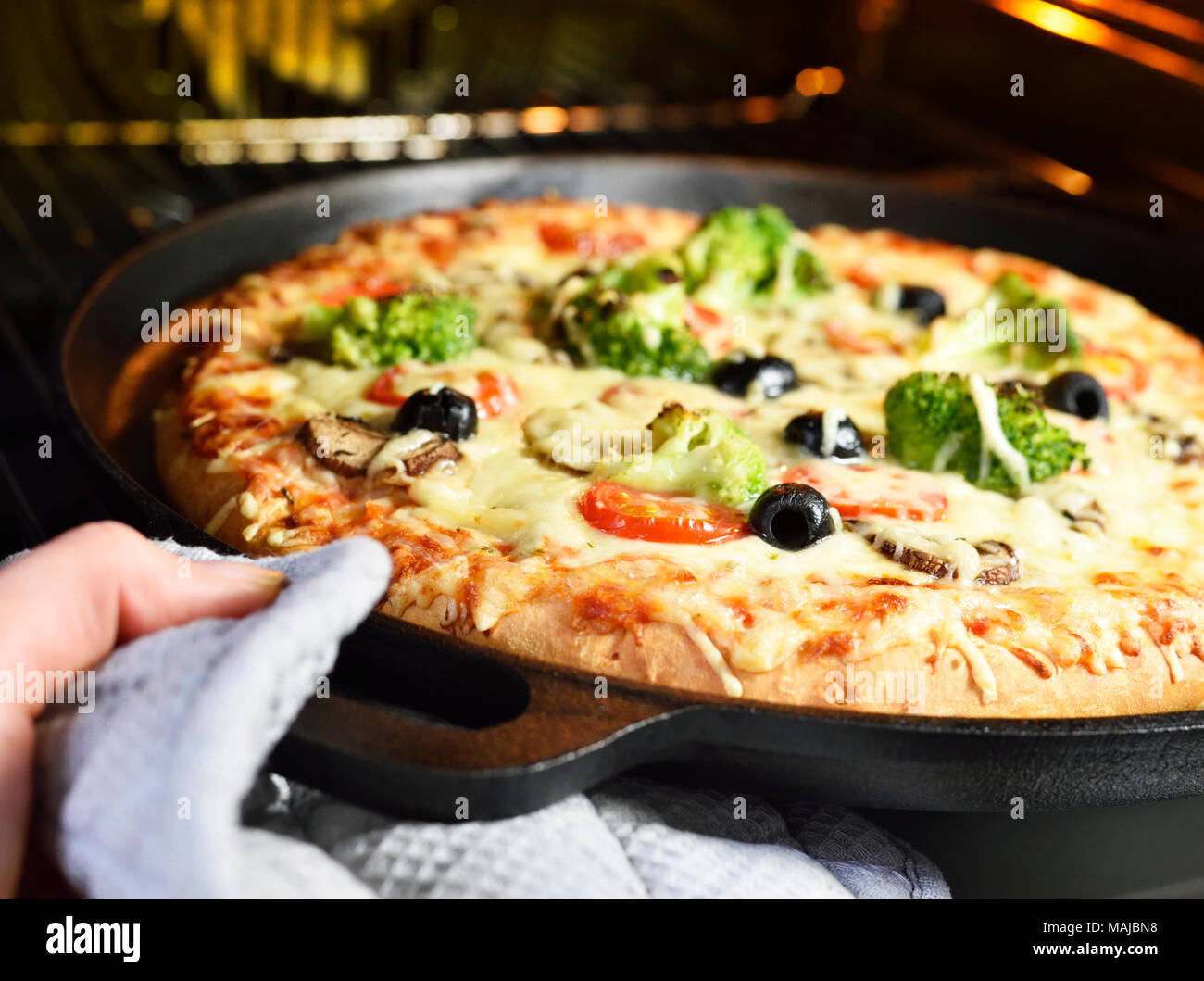 Hausgemachte Pizza. Vegetarische Pizza im Pizza pan, Gemüse Pizza mit Brokkoli, Champignons, Tomaten und Oliven. Pizzabacken Szene. Stockfoto