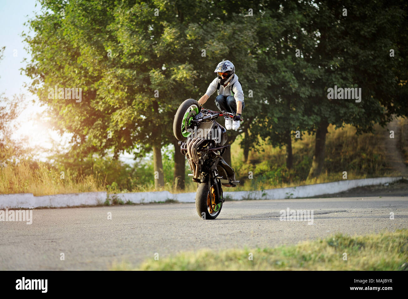 Ternopil, Ukraine - 28. August 2015: Männlich Biker ist Ausbildung in die Tricks auf Sport Motorrad auf Sommer zitieren Straße. Grüne Bäume im Hintergrund. Das Tragen von Helm. Stockfoto