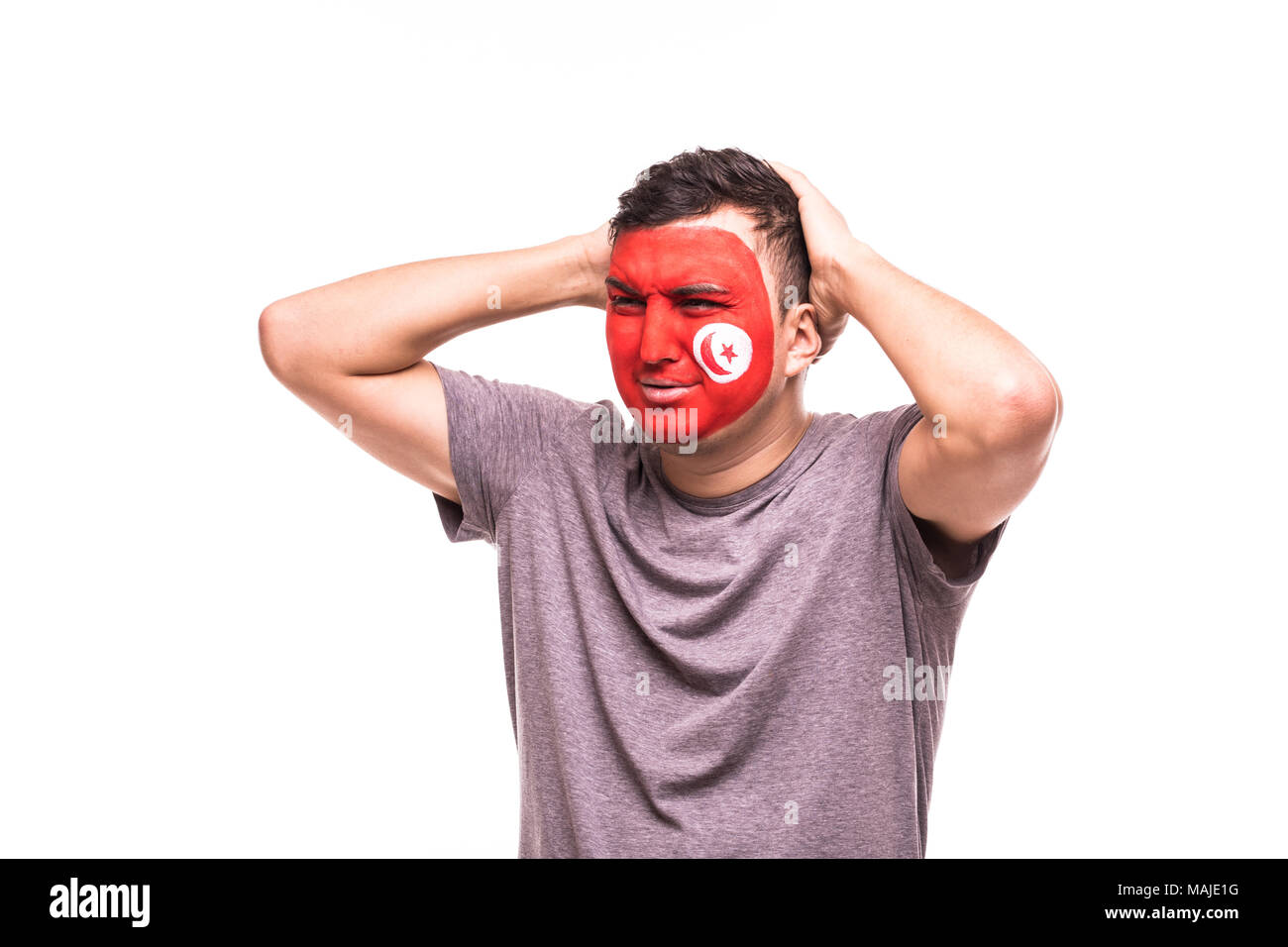 Verärgert Verlierer fan Unterstützung der tunesischen Nationalmannschaft mit bemaltem Gesicht isoliert auf weißem Stockfoto