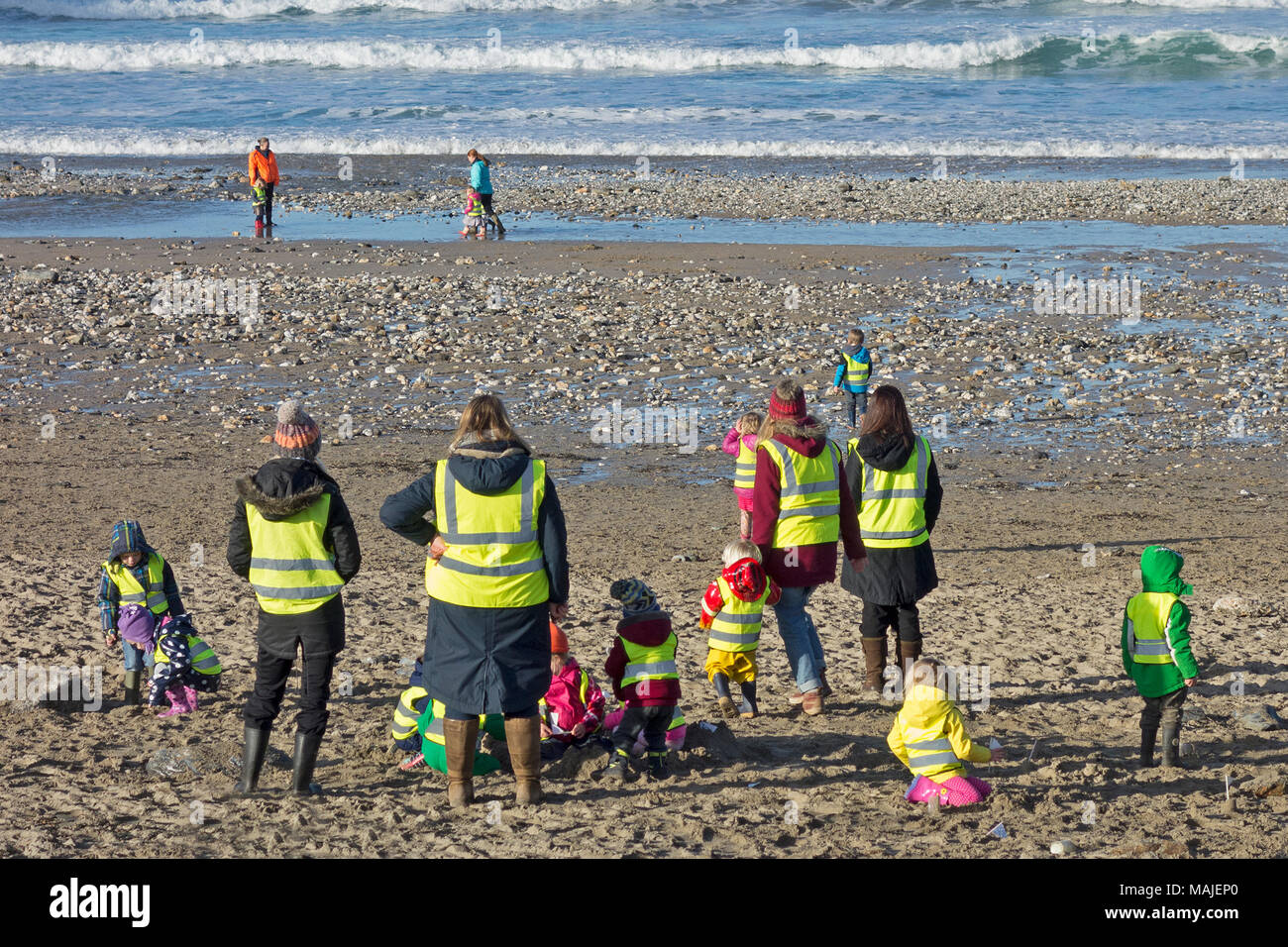 Vorschule Kindergarten Kindergarten Kinder mit Lehrern und Betreuern in einer Lektion am Strand in Cornwall, England, Großbritannien. Stockfoto