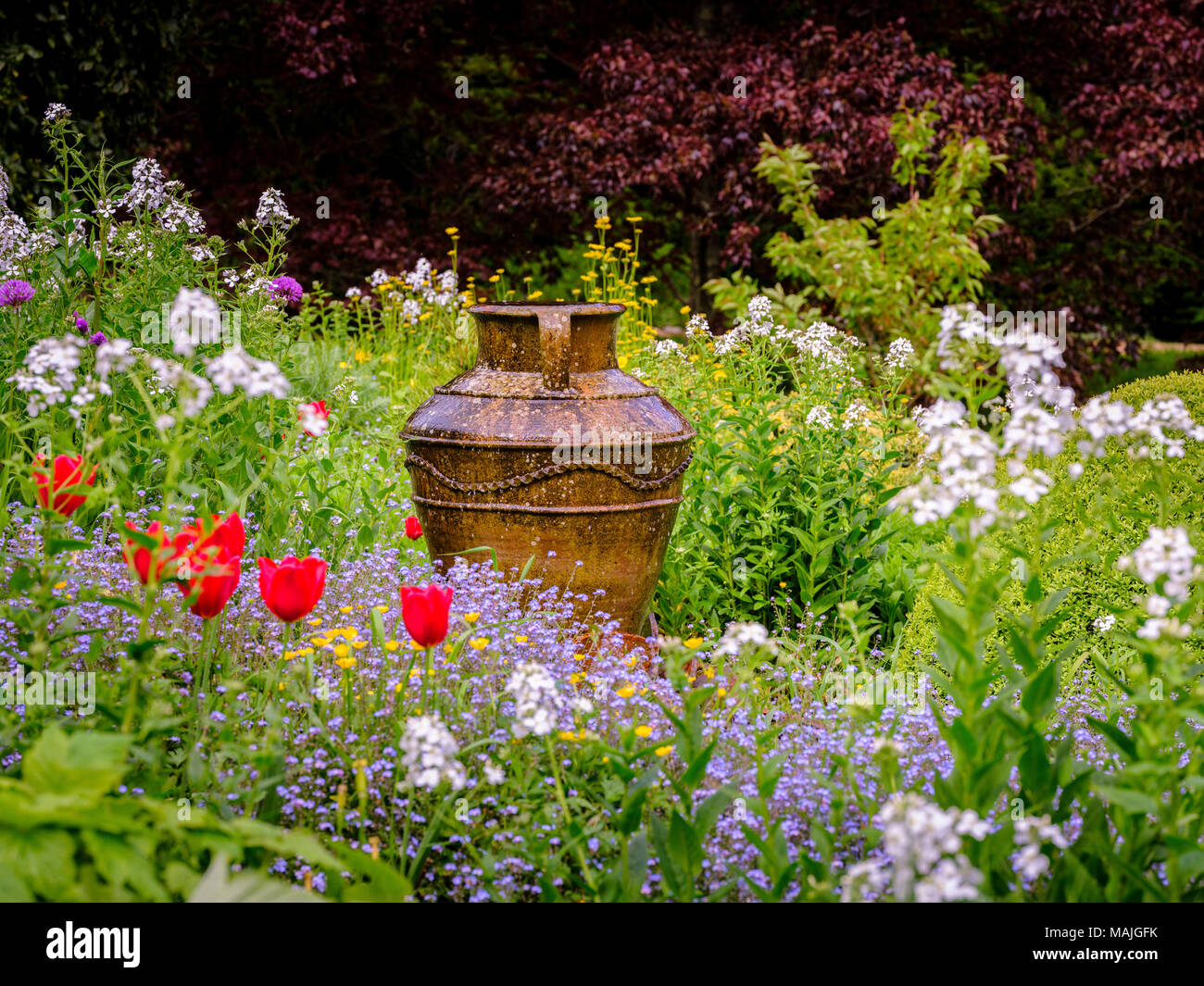 Eine kunstvolle Urne in der Mitte eines blühenden Garten. Stockfoto