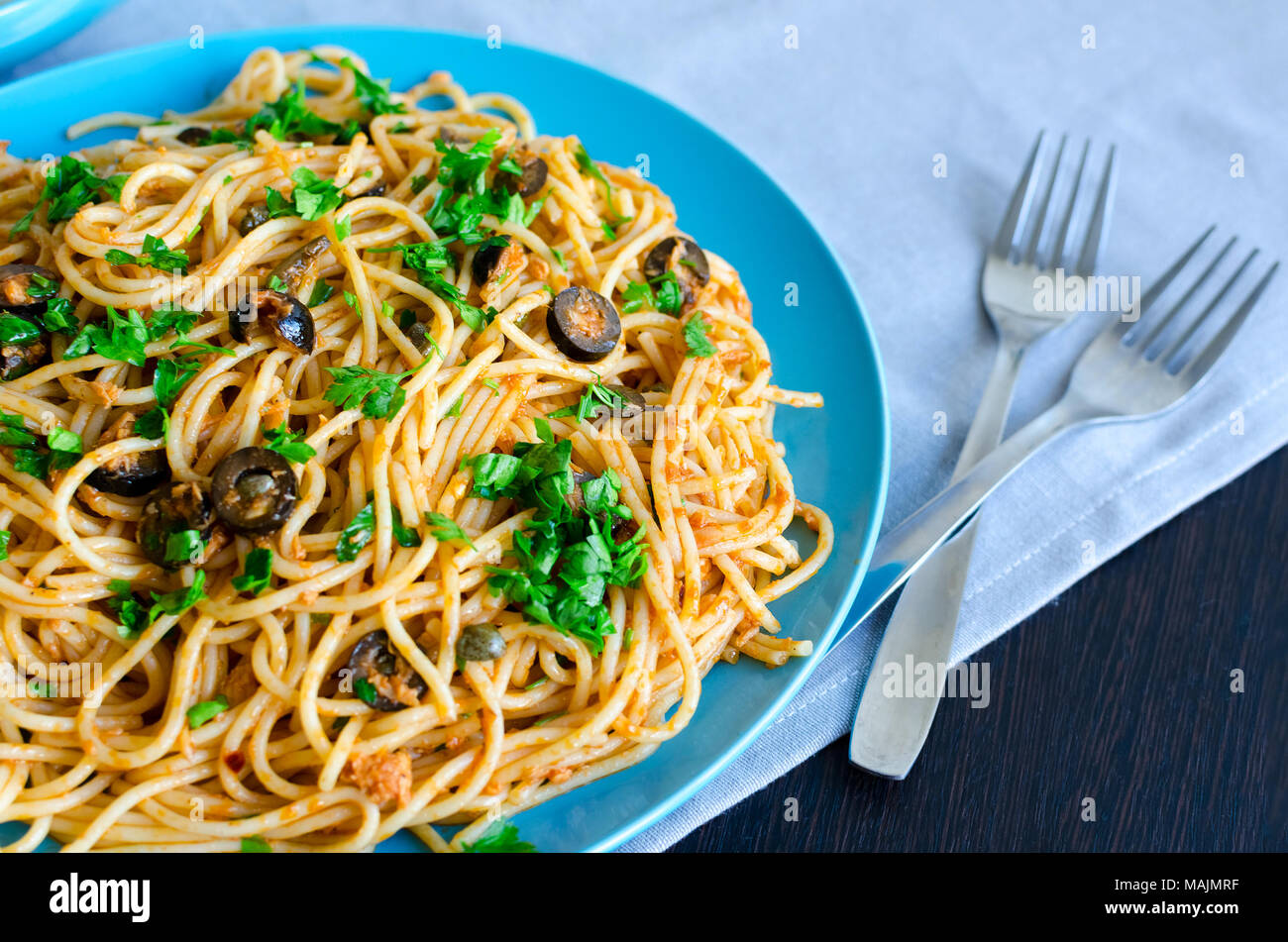 Spaghetti alla Puttanesca - traditionelle italienische Pasta mit schwarzen Oliven, Thunfisch, Sardellen, Kapern und Petersilie. Vegetarisches Essen. Italienische Küche. Stockfoto