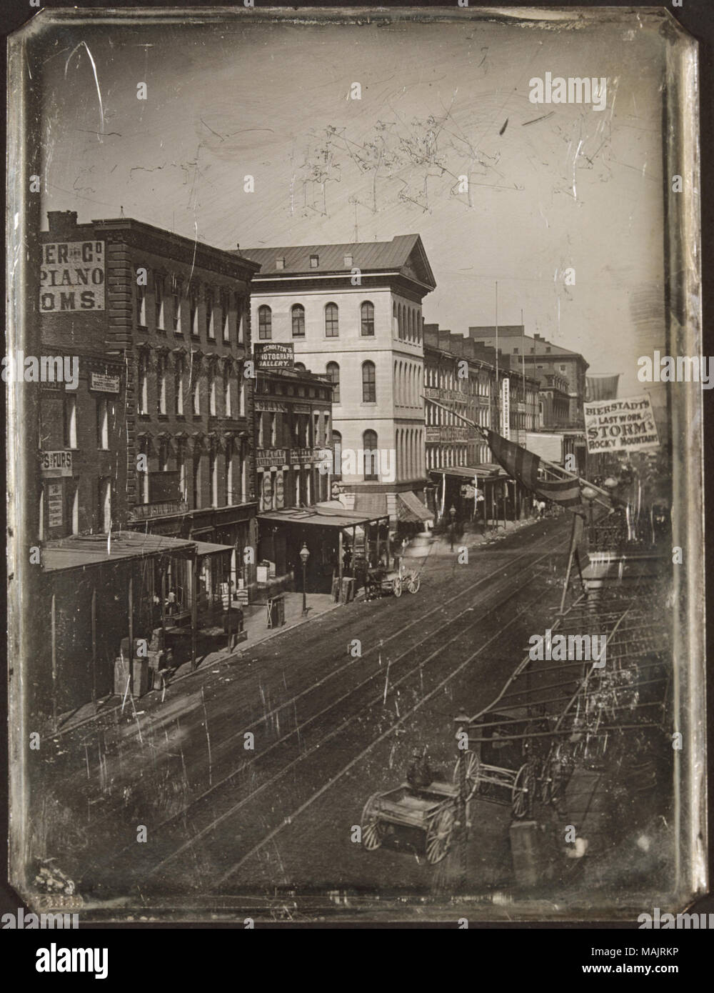 Pferde mit Wagen auf der Vierten Straße um ihrem Schnittpunkt mit der Locust Street. Kommerzielle Gebäude säumen die Straßen, J. A. Scholtens Fotogalerie, Grey's Hut und Cap Hersteller, E.Clark's Nähmaschine Depot, Frau Davis' Vernaison und Geschenkartikeln, Emmet und Shea Textilhändler und Bierstadt's gehören. Eine amerikanische Flagge hängt über der Straße. Die Unterseite der Metall Matte hat 'MArchen' eingebettet in Sie. Titel: die vierte Straße nach Norden zum Schnittpunkt mit der Locust Street. . 1867. Thomas M. östlich Stockfoto