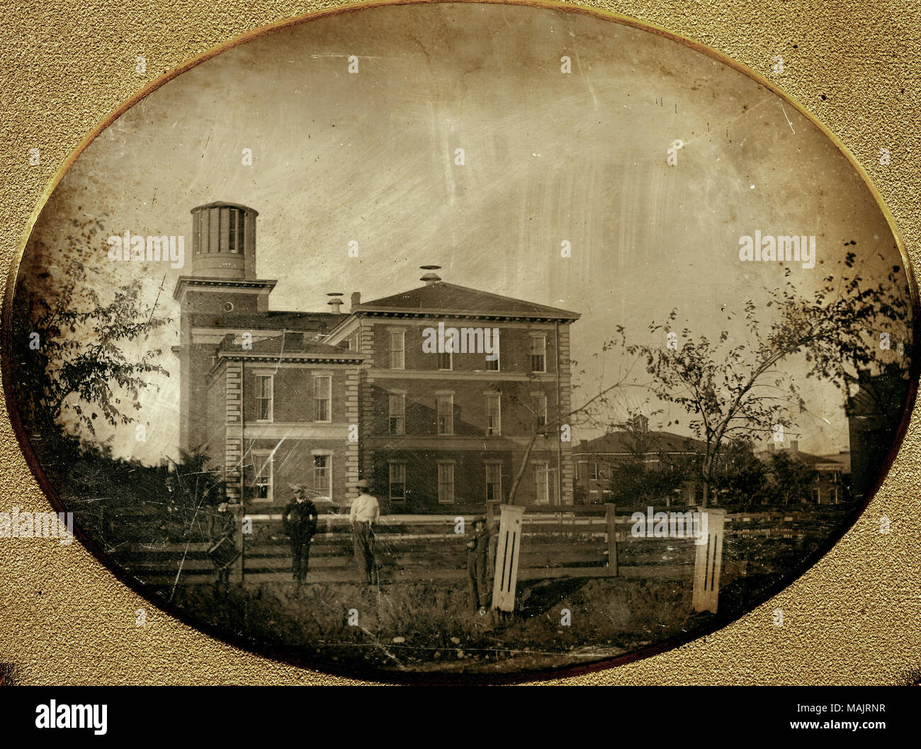 Vier Jungs stehen in der Nähe von einem Zaun vor der Washington Universität akademische Hall und Smith Akademie. Hält man eine Trommel und ein anderer hält einige Bücher und lehnt sich gegen eine von zwei großen, schlanken Baum Pflanzer im Vordergrund. Viele Gebäude können hinter Ihnen und Sie nach rechts gesehen werden. Titel: Washington University Akademische Hall und Smith Akademie. . 1856. Thomas M. östlich Stockfoto