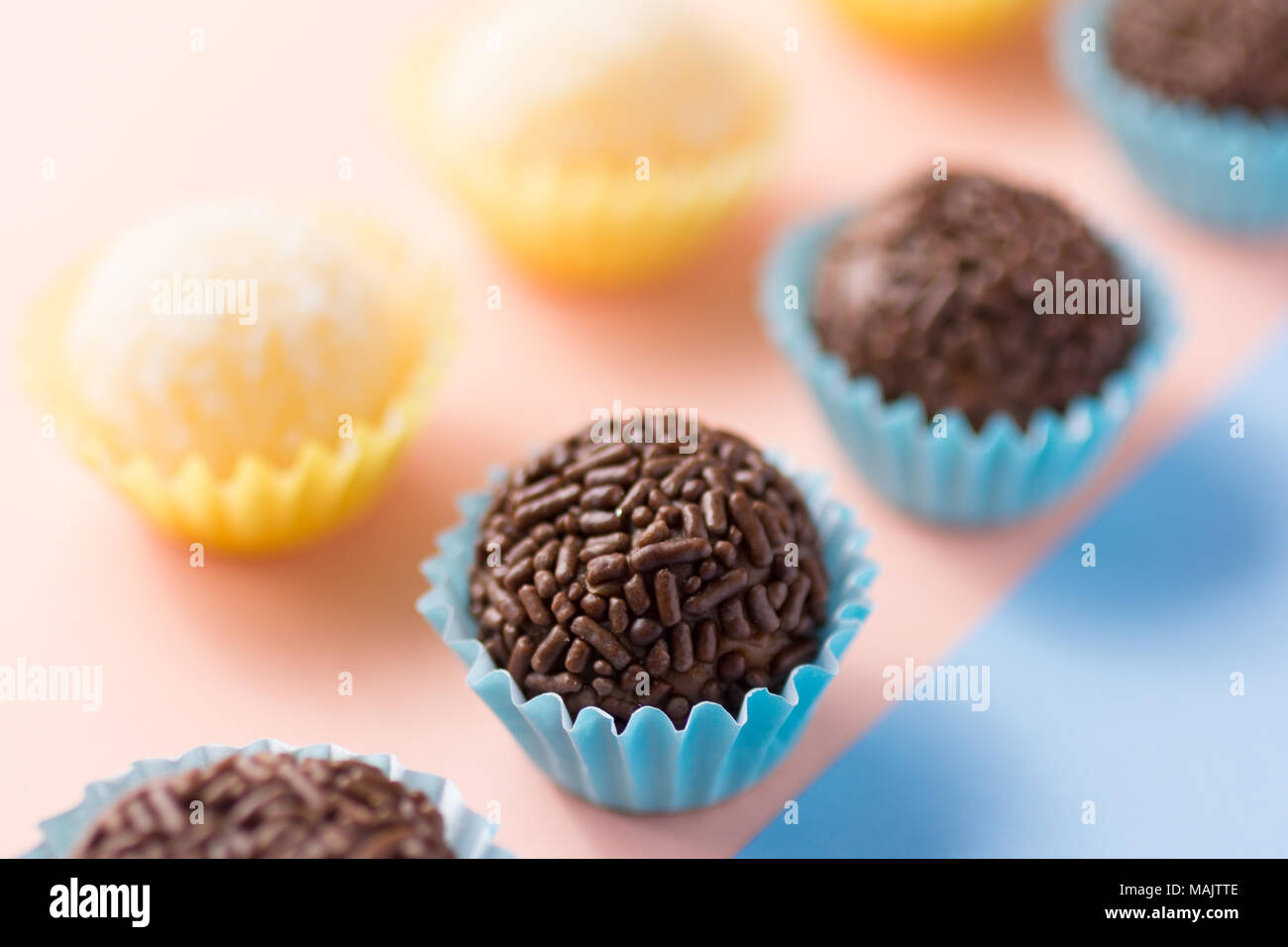 Handgemachte brasilianische Spezialitäten: Beijinho und Brigadeiro. In den Kindergeburtstag. Candy Kugeln in einer geraden Linie. Bunter Hintergrund. Stockfoto