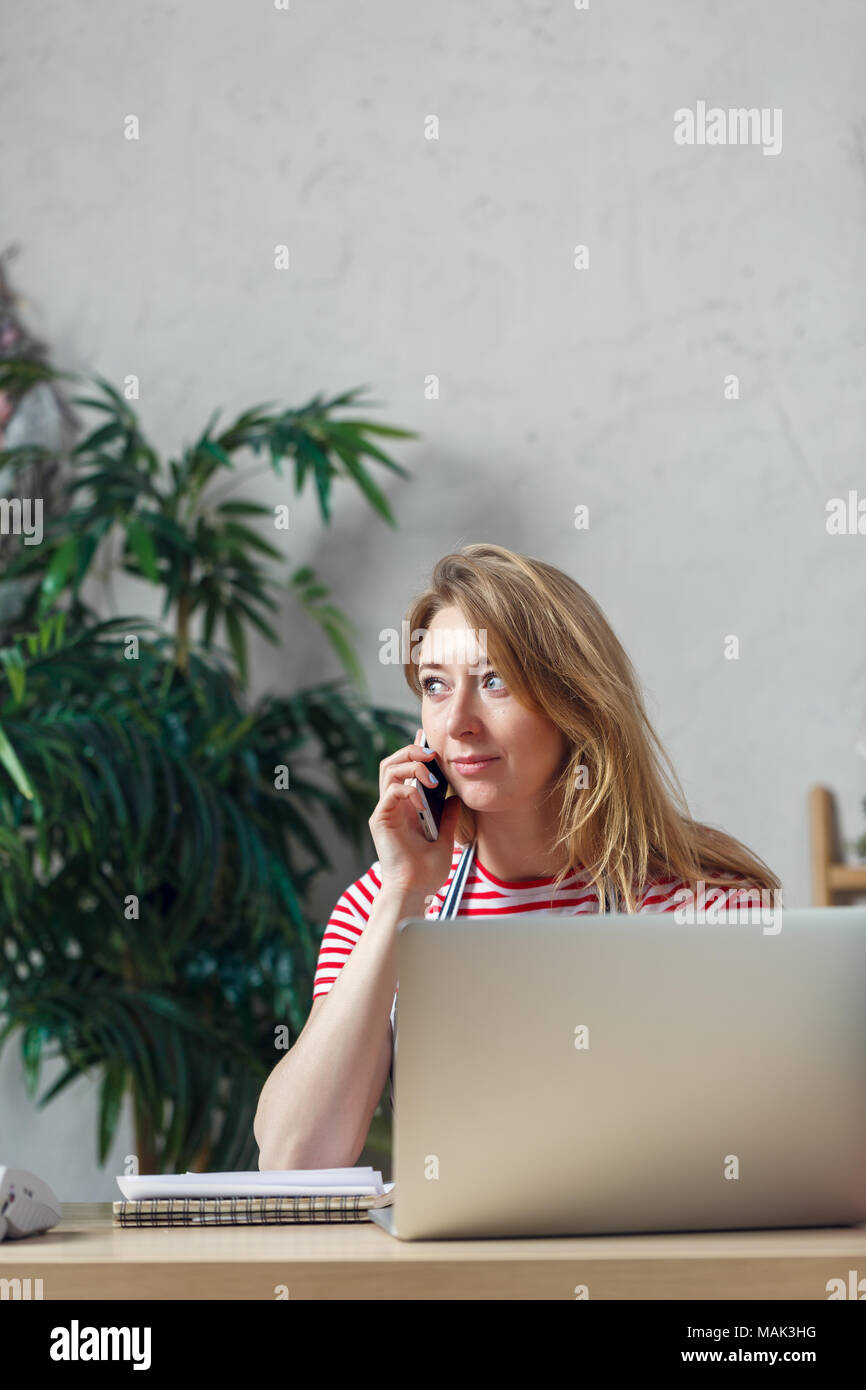 Bild des Blonden blumengeschäft am Telefon sprechen am Tisch sitzen mit Computer Stockfoto