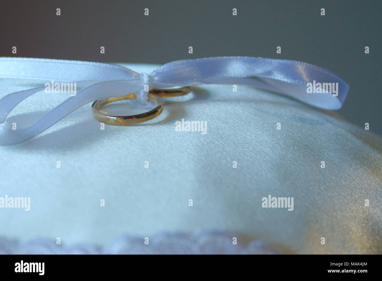 Eine weiße Schleife in einer Schleife gebunden hält Hochzeit Ringe auf einem Kissen. Stockfoto