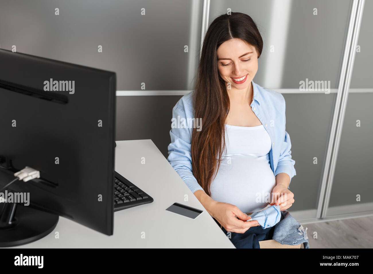 Schwangere Frau shopping online. Die werdende Mutter kaufen Kleidung für Ihr Baby und Zahlung per Kreditkarte. Schwangerschaft, Technologie, Erwartung, Baby, auf Stockfoto