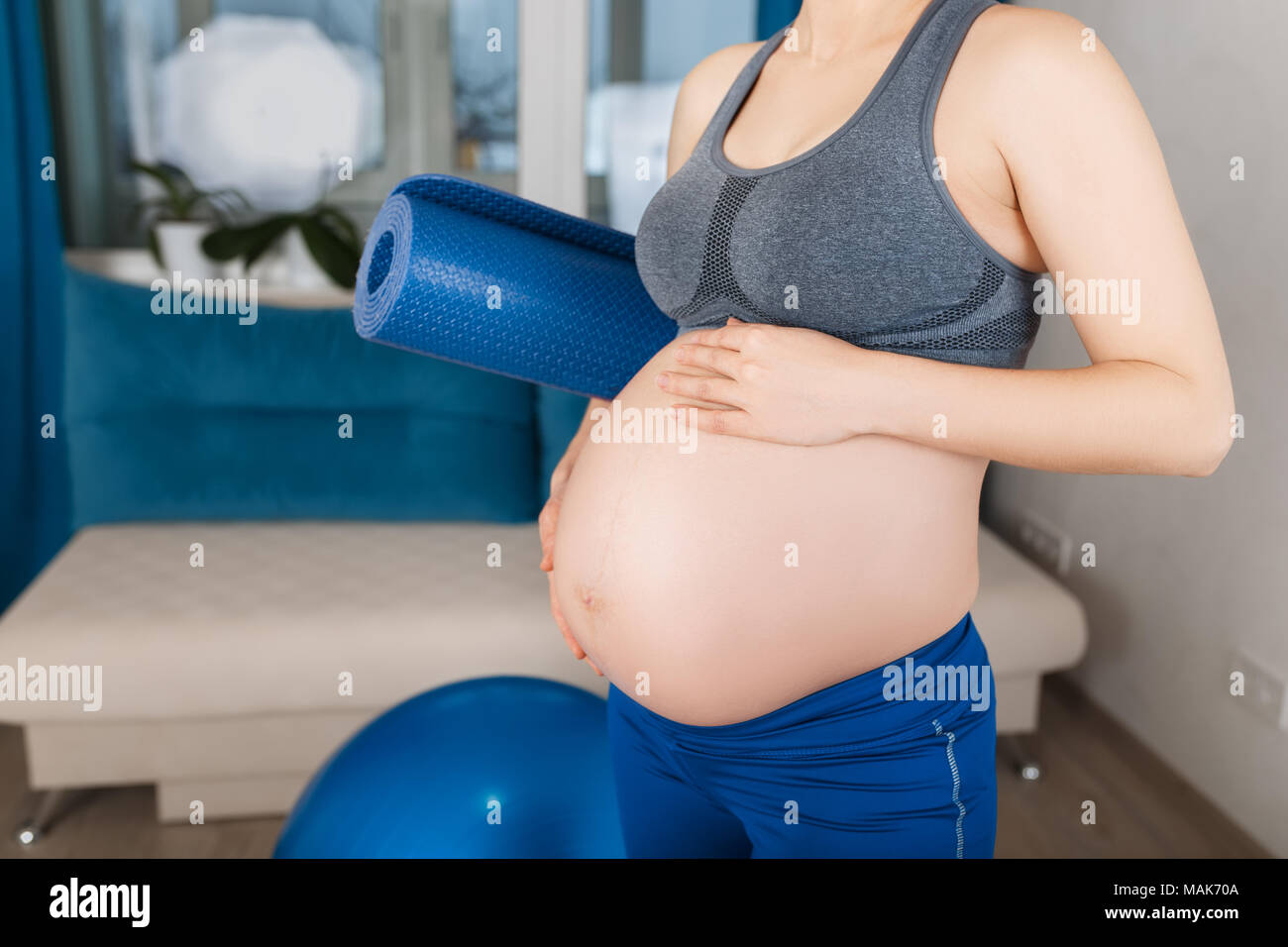 Closeup schwangere Bauch. Schwangere Frau mit Yoga Matte zu Hause. Die werdende Mutter nach der Gymnastik. Schwangerschaft, Gymnastik für Schwangere, gesunden Lebensstil Stockfoto