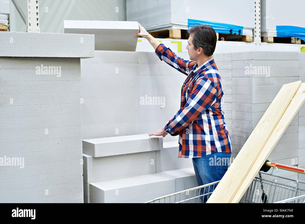 Mann wählt und kauft Schaumbeton Ziegelsteine in einem Supermarkt Stockfoto