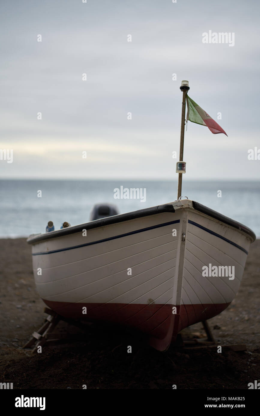 Vorderansicht eines leeren Boot mit Flagge am Strand der Küste von Amalfi, Italien während bewölkt Abend geparkt. Stockfoto