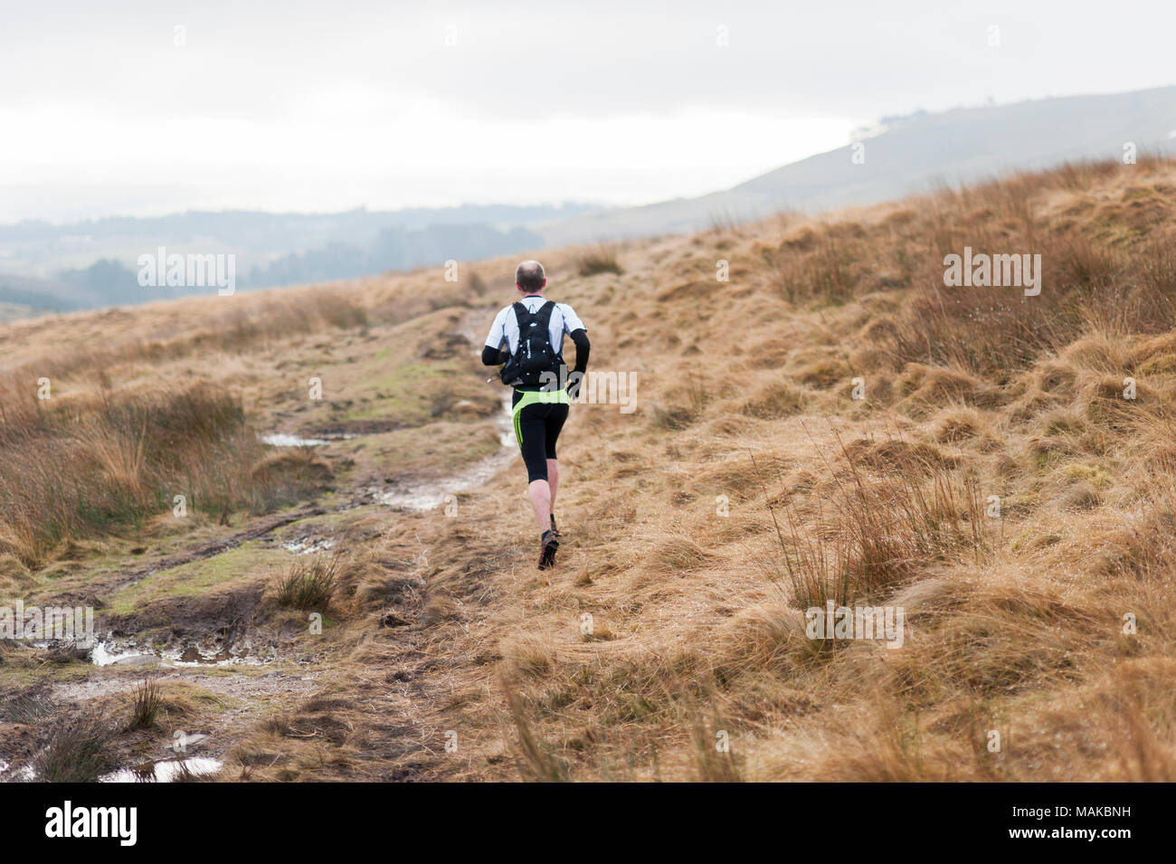 Ein Mann wird gesehen, die entlang einer schlammigen Pfad in den Hügeln auf einem kalten und nassen Nachmittag Stockfoto