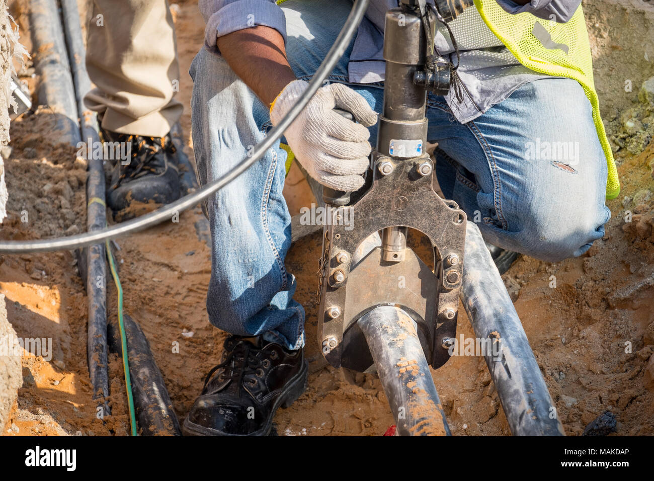 Eine Electrican schneiden heavy duty 11 kv3 Core elektrische Kabel auf der Baustelle Stockfoto