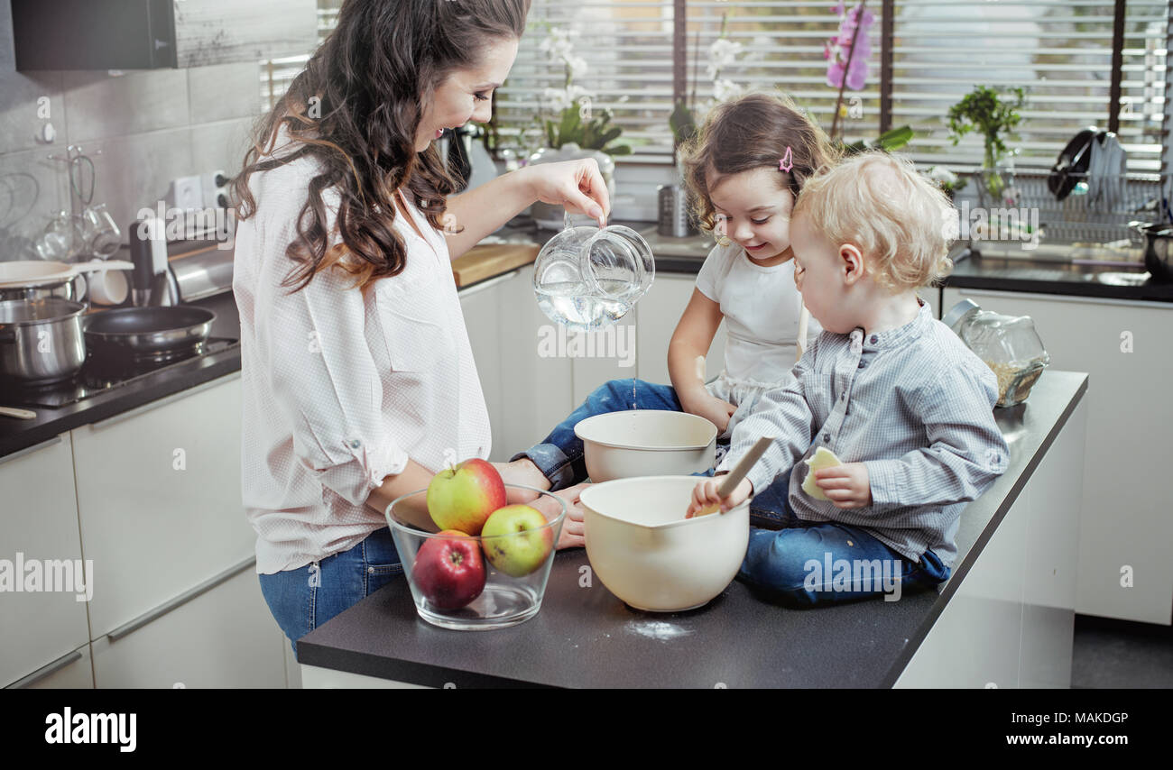 Ruhige Mutter ihre Kinder lehren, wie man einen Kuchen backen Stockfoto