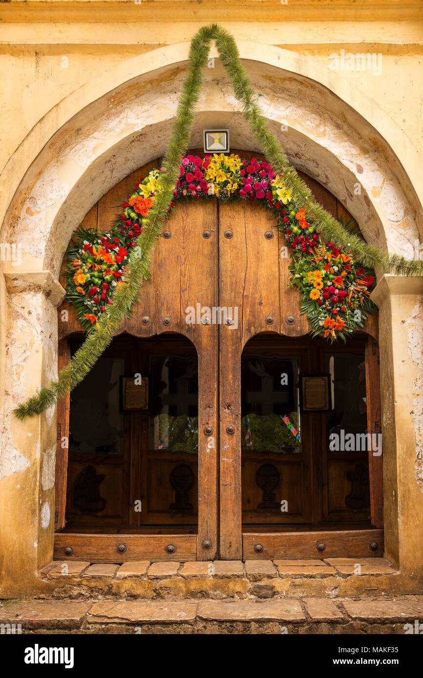 Alte hölzerne Kirche Türöffnung mit Blumen bedeckt Stockfoto