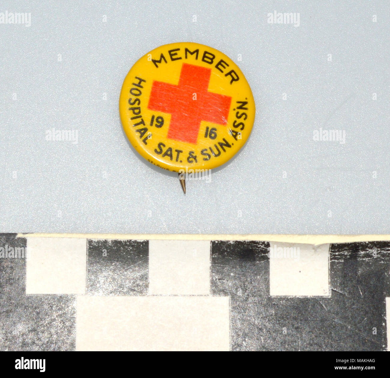 Klein, rund, gelb Stift mit einem roten Kreuz. Bedeutet, dass ein Mitglied des Krankenhaus Samstag und Sonntag Verbindung von New York. Gedruckt von der St. Louis Taste Co.Titel: Krankenhaus Samstag und Sonntag Association Pin. 1916. St. Louis Taste Co. Stockfoto