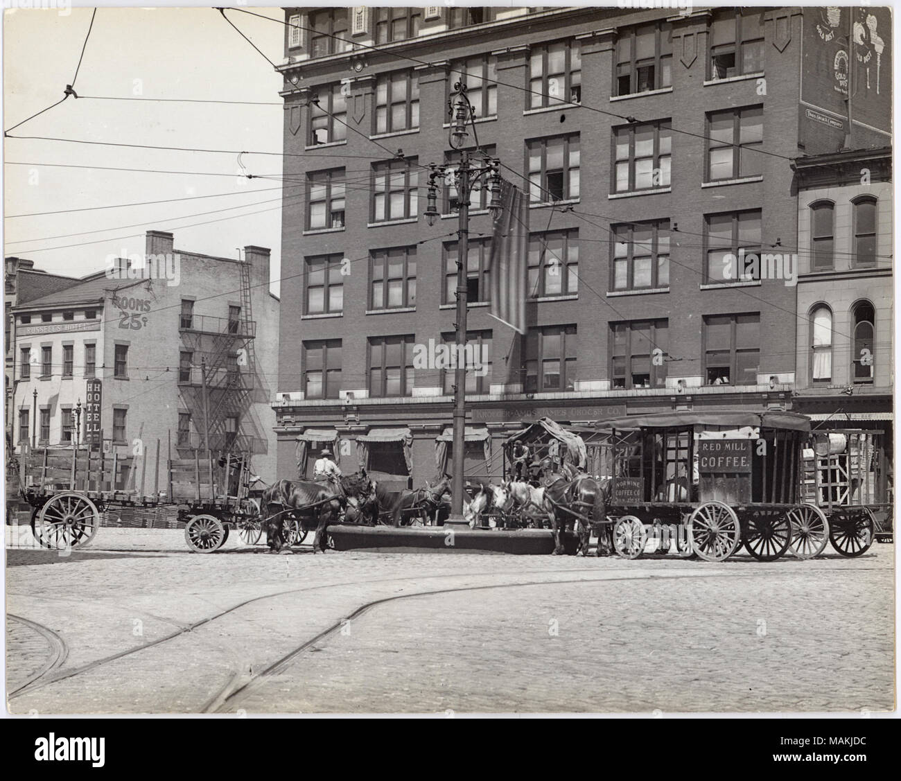 Horizontal, schwarz-weiß Foto zeigt ein Pferd Trog 3. Straße, entweder auf der Washington Avenue oder Lucas Avenue. Pferde ziehen eine Vielzahl von Wagen und Karren sind gezeigt das Trinken aus dem Trog. Zeichen auf den Wagen gehören "Rote Mühle Kaffee' und 'Norwine Coffee Co./311 N 2.St". Mehrere Gebäude sind im Hintergrund gezeigt, darunter auch Russell's Hotel, wahrscheinlich bei 700 North 3rd Street und Kroeger-Amos - James Lebensmittelhändler Firma, wahrscheinlich bei 620 North 3rd Street. Ein typisiertes Hinweis auf der Rückseite der Drucken, möglicherweise eine Ausstellung caption, liest 'Pferd Trog. 1911. Third Street in Washington und Luc Stockfoto