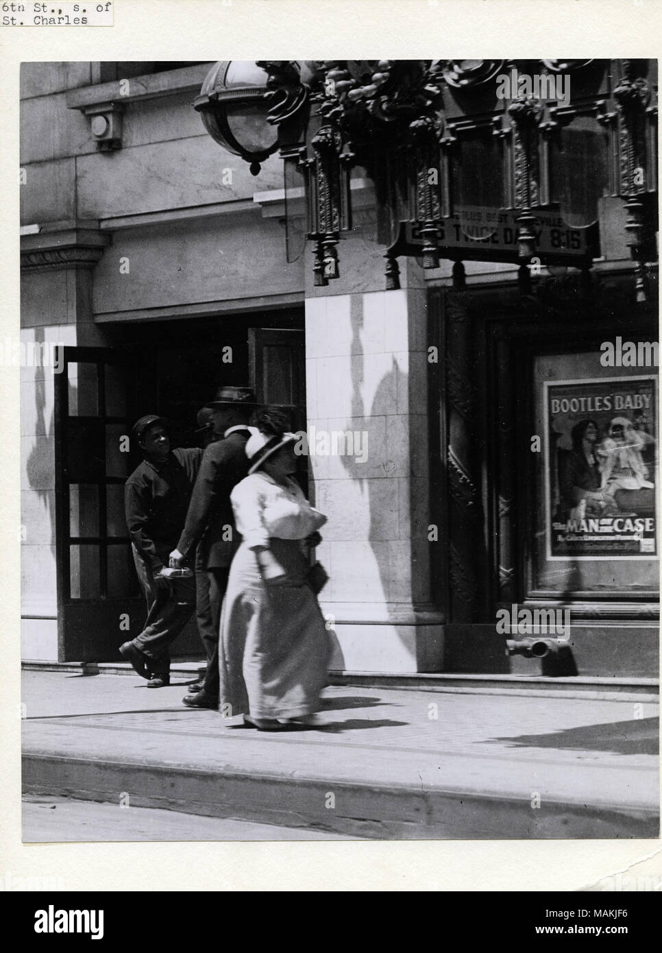 Vertikal, schwarz-weiß Foto zeigt eine Frau auf dem Bürgersteig vor der Strand und Columbia Theater an 419 und 425 North 6th Street. Eine kleine Gruppe von Männern steht hinter ihr. Eine reich verzierte Überhang kann in der oberen rechten Ecke zu sehen. Ein Plakat werbung die Filme Sicherheitsspiegel ' Baby und der Mann in der Fall unter dem Überhang gesehen werden kann. Titel: Frau, eine Gruppe von Männern, die auf dem Bürgersteig vor dem Strand und Columbia Theater an 419 und 425 North 6th Street. . Um 1914. Holt, Charles Clement, 1866-1925 Stockfoto