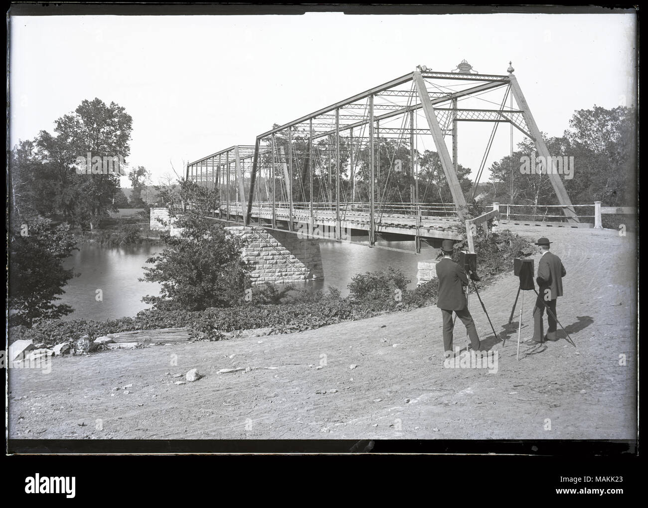 Horizontal, schwarz-weiß Foto zeigt eine Brücke über einen Fluss. Zwei Männer stehen auf der rechten Seite des Bildes neben Stative mit dem Rücken zum Betrachter. Titel: Zwei Fotografen bei der Arbeit neben dem Fenton Brücke. . 1895. Stockfoto