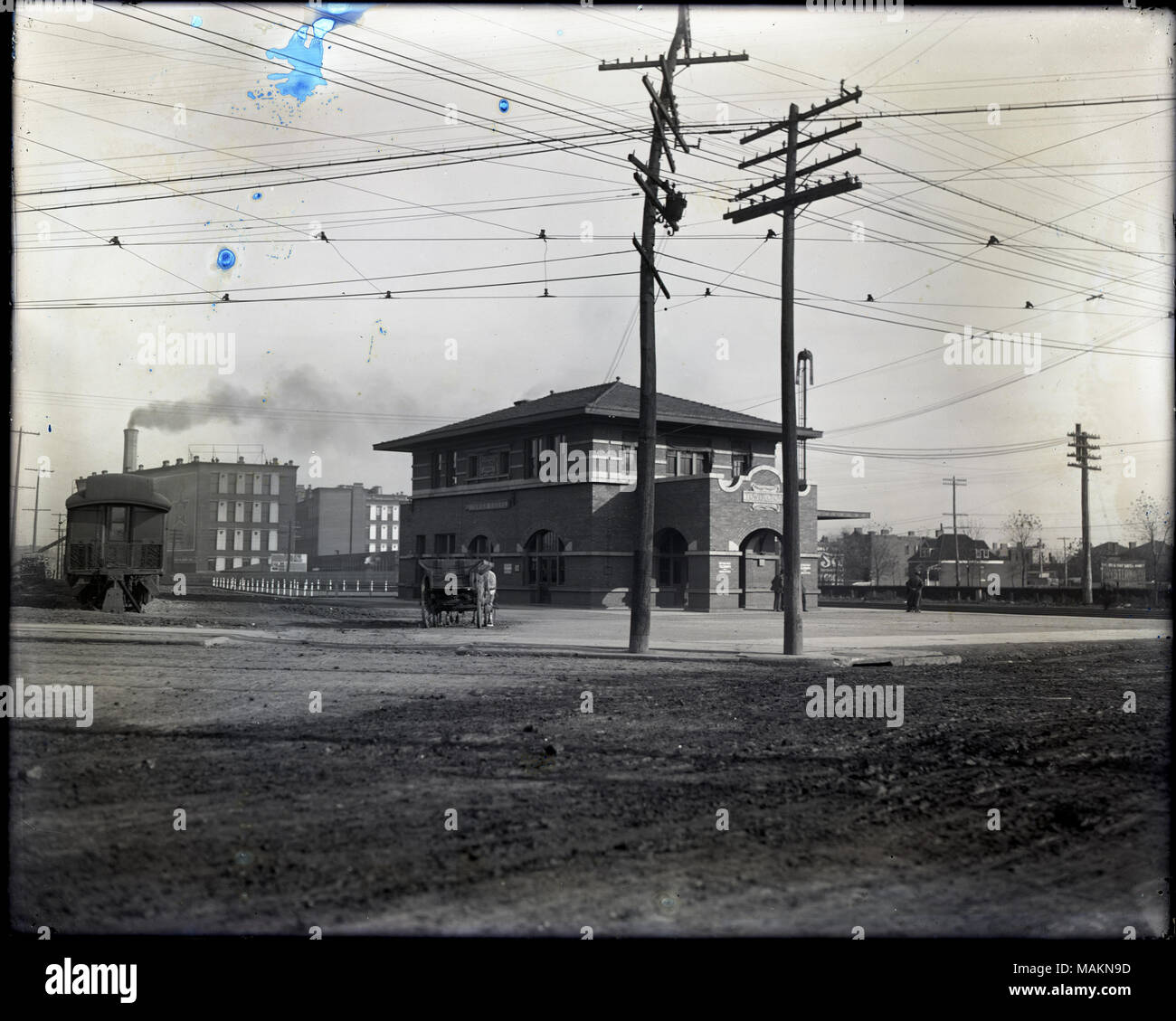 Horizontal, Schwarz und Weiß Foto, Tower Grove entfernt. Das Bahnhofsgebäude befindet sich in der Mitte des Fotos, und ein Zug Auto ist auf der linken Seite. Es ist eine Straße im Vordergrund. Zwei utility Pole und ein Pferd auf einem Wagen angekuppelt werden im mittelgrund vor dem Gebäude. Titel: Tower Grove entfernt. . Um 1910. Stockfoto