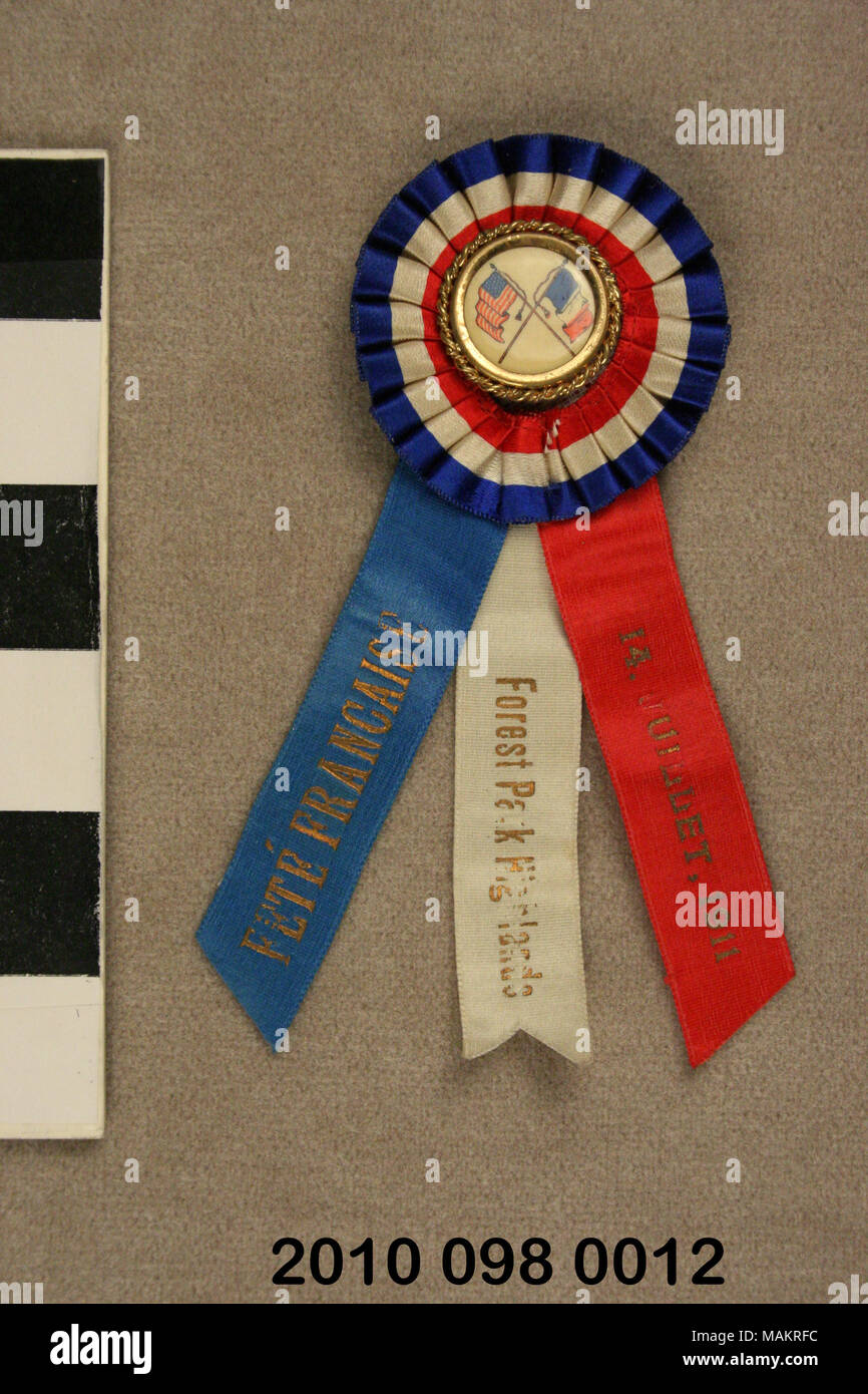 Stift mit runder Knopf mit französischen und amerikanischen Flaggen durch ein Plissee runde rote, weiße und blaue Rosette umgeben. Drei Bänder hängen unten 1911 Fete Francaise eingeprägt. Titel: Stift mit Band von 1911 Fete Francaise. 1911. Stockfoto