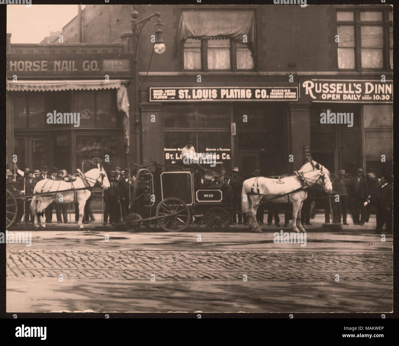 Horizontal, schwarz-weiß Foto einer Gruppe von Straße Wartung Arbeiter bis an den Rand des Bürgersteigs und Pferd gefüttert - Straßenreinigung gegen den Bürgersteig geparkt. Eine Reihe von Backstein kommerzielle Gebäude lesen 'St. Louis Beschichtung Co." und "Russell's Dinner" sind hinter der Arbeitnehmer. Titel: St. Louis Beschichtung Unternehmen. Tucker und Market Street. . Zwischen ca. 1800 und ca. 1900. Swekosky, William G., 1895-1964 Stockfoto