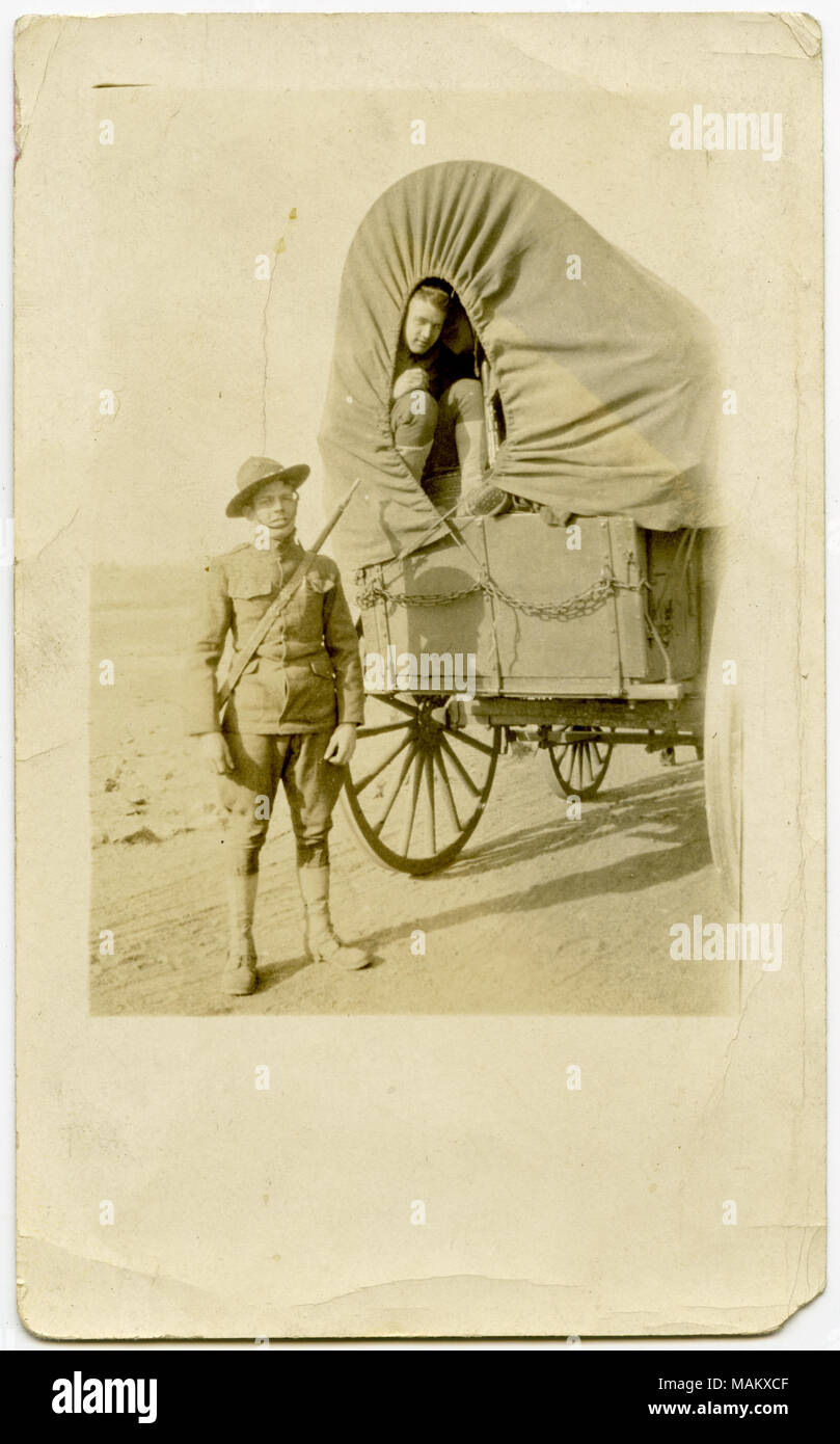 Vertikale, sepia Foto, ein Mann in Uniform neben einem Leinwand - Planwagen auf einem Feldweg. Ein uniformierter Mann sitzt im Inneren der Leinwand - Planwagen. Geschrieben auf der Rückseite des Fotos ist der Name "Harry." Titel: ein Soldat steht neben einem Wagen auf einer Schotterstraße, die Ein anderer Soldat hält. . Zwischen ca. 1916 und ca. 1918. Stockfoto