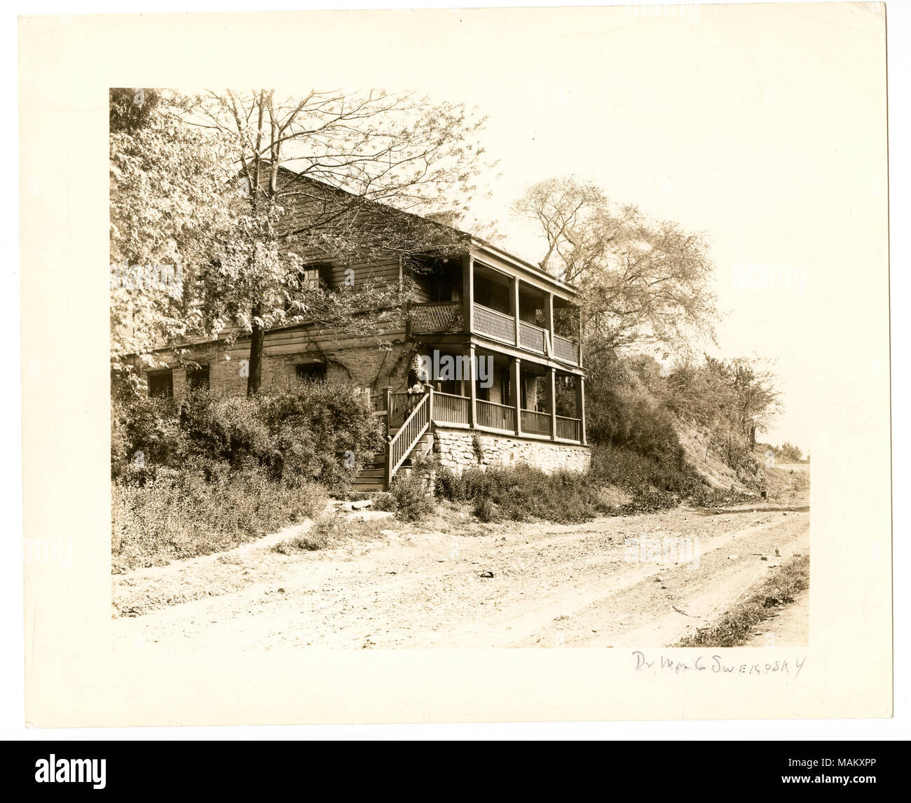 Horizontal, schwarz-weiß Foto eines zweistöckigen Holz- Abstellgleis und Haus aus Stein. Der zweigeschossige Balkon hat ein Gitter Geländer auf der zweiten Ebene und eine Frau und Kind stand auf der hölzerne Tor Eingang auf der ersten Ebene. Eine Piste ist vor der Residenz sichtbar. Titel: Guion, Vincent Residence. 5815 Pennsylvania. . 1894. Stockfoto