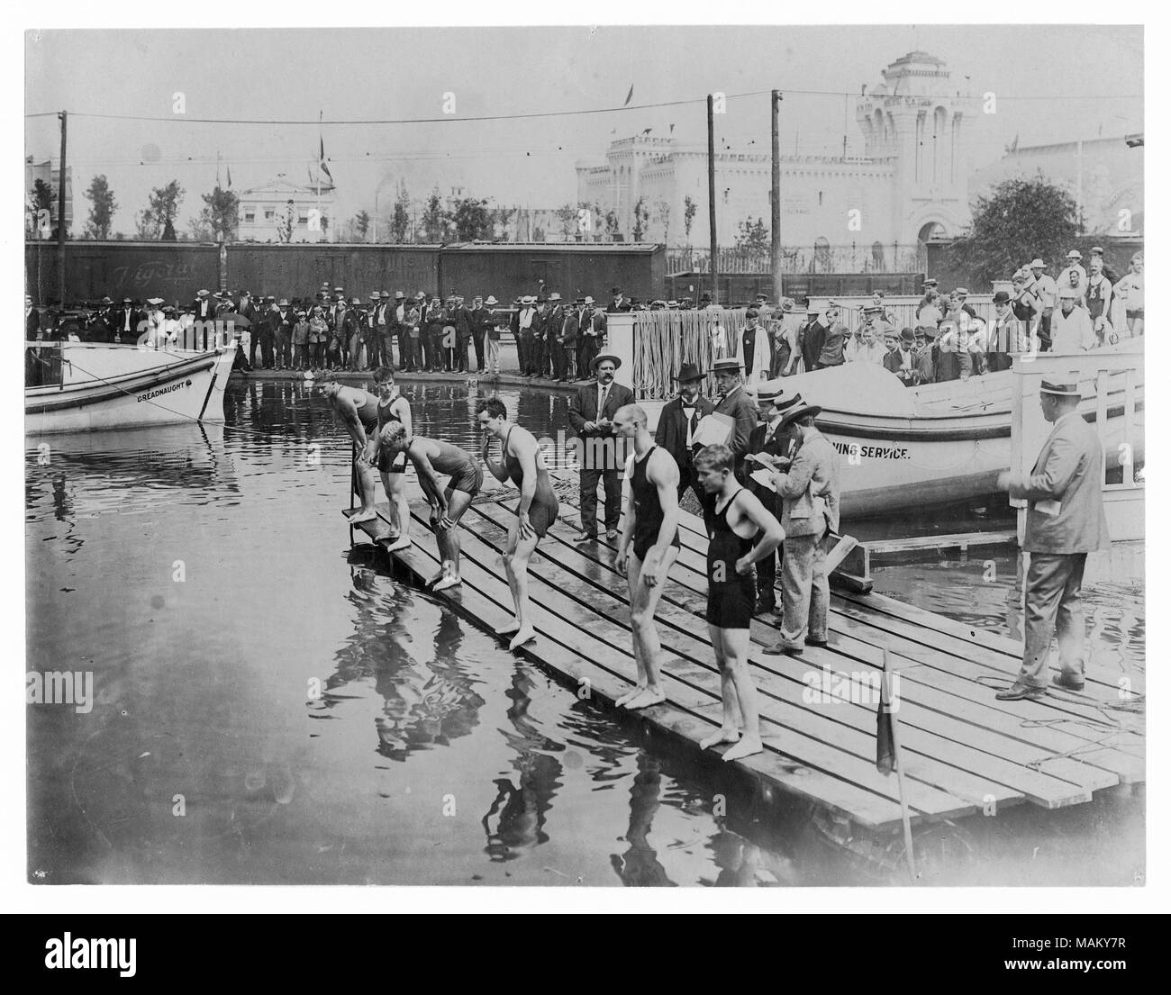 Horizontale Foto von sechs Schwimmer die Vorbereitung für den Beginn der Hitze. Eine Menschenmenge steht am Ufer und Richter stehen hinter der Schwimmer. Titel: 1904 Olympics: Fünfzig Meter langen Strich, die Hitze. Olympia: Fünfzig Meter langen Strich, die Hitze. Foto 1904 Missouri History Museum Foto und Print Collection. n 15651 Stockfoto