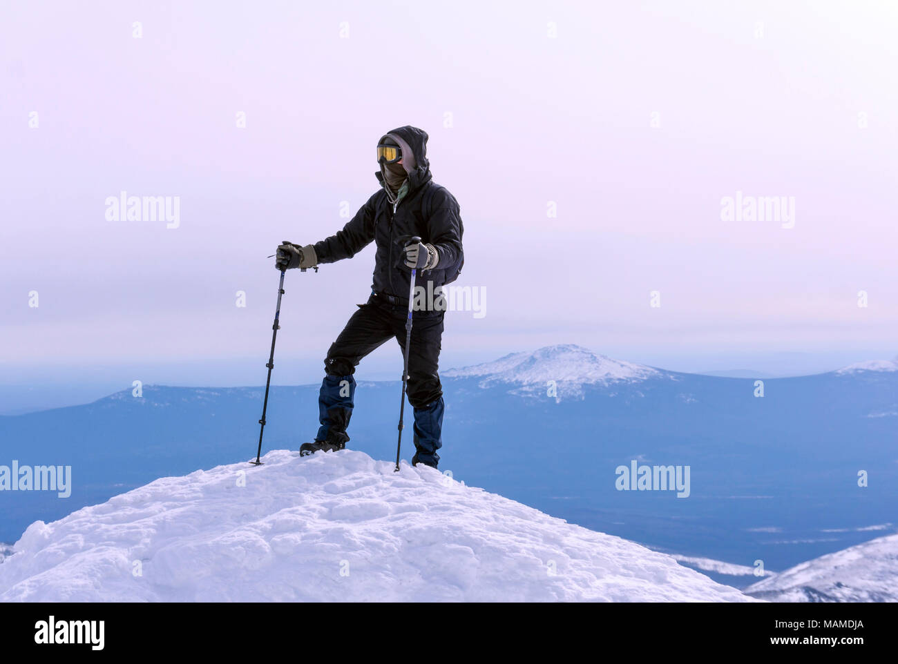 Kletterer in eine winddichte Maske und Brille erreicht der Schnee oben auf dem Berg Stockfoto