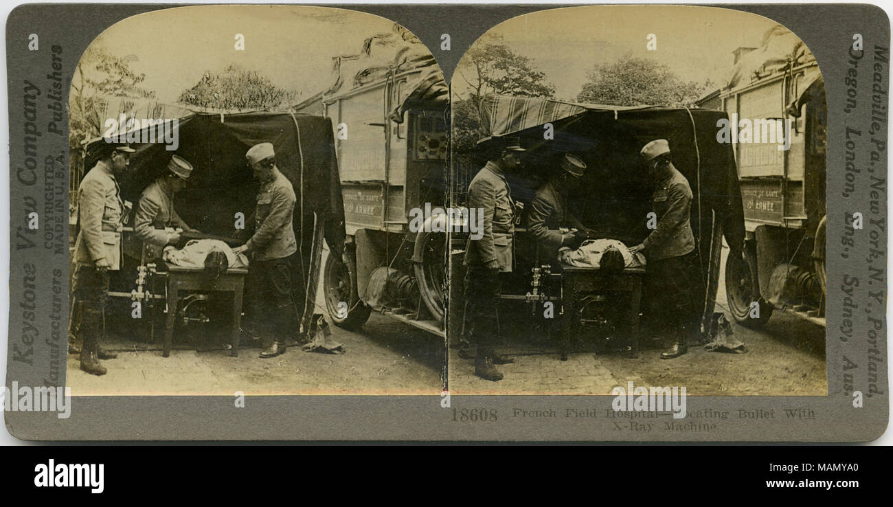 Horizontale, Sepia stereocard zeigt drei uniformierte Männer, die ein x-ray von einem Mann lag auf einem Tisch. Keystone Stereograph Nummer 18608. Der Titel lautet: "Französische Feldlazarett - Suche Bullet mit X-Ray Machine." Titel: "Französische Feldlazarett - Suche Bullet mit X-Ray Machine'. . Zwischen ca. 1914 und ca. 1918. Keystone View Company Stockfoto