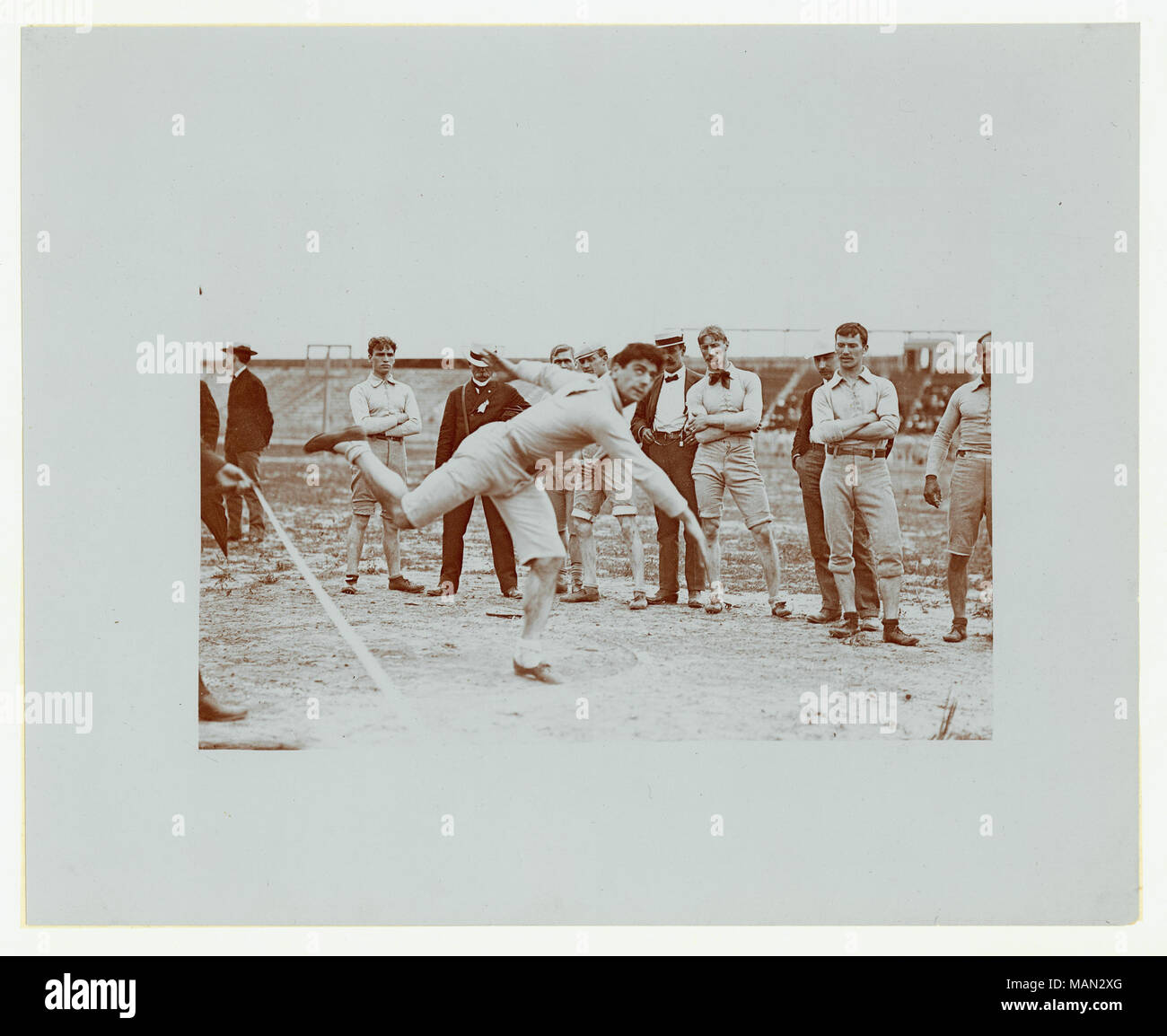 Horizontale Foto von "Turnverein kombinierte Übung, Kugelstoßen, nicht identifizierter Wettbewerber". Die Konkurrenz hat gerade das Kugelstoßen und andere Athleten und Männer in streetclothes, vielleicht Richter entlassen. Titel: Kugelstoßen Konkurrenz an der Turner Spiele. . Juli 1904. Louis Melsheimer Stockfoto