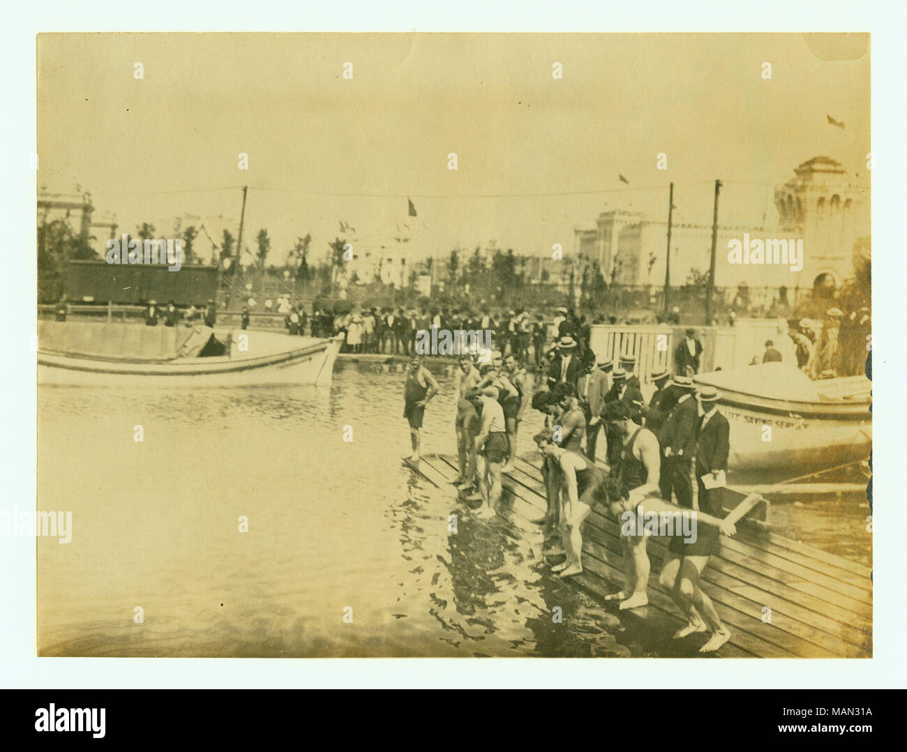 Horizontale Foto einer Plattform mit mehreren Schwimmer auf, von denen einer beginnt zu tauchen. Es gibt Massen entlang der Küste und zwei Boote im Wasser. Titel: Start der 440 Yard schwimmen Wettbewerb mit Handicap, 1904 Olympics. . 1904. Stockfoto