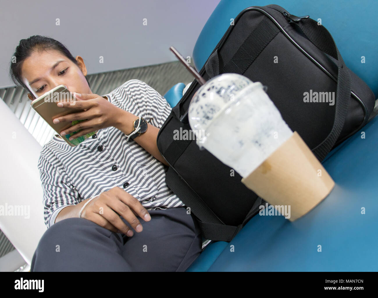 Eine junge Frau mit Handy im Wartezimmer sitzen. Reisende wartet auf seine Verkehrsanbindung. Am Flughafen. Stockfoto