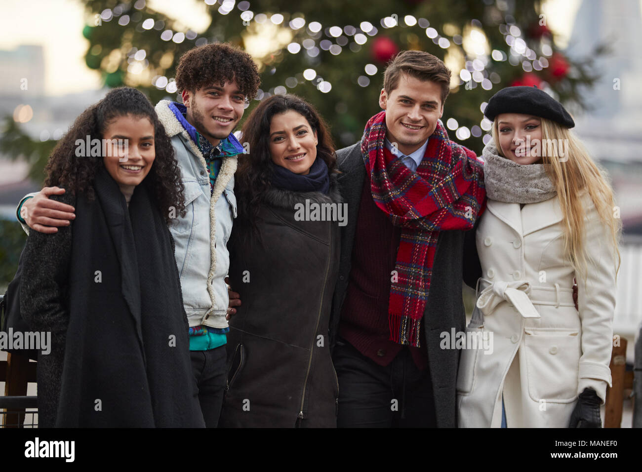 Porträt der jungen Freunde zu Fuß stehend durch Weihnachtsbaum Stockfoto