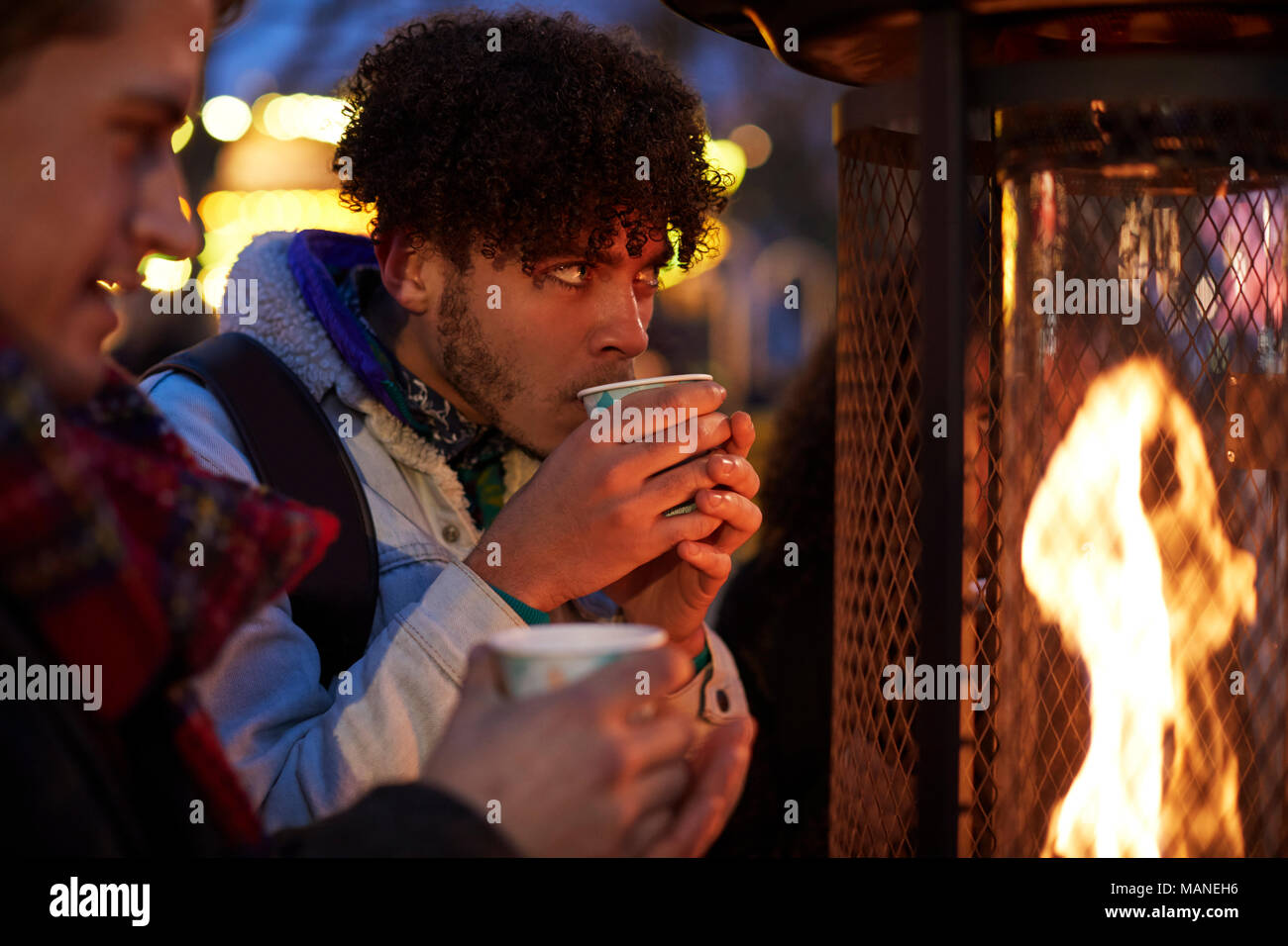 Männliche Freunde trinken Glühwein am Weihnachtsmarkt Stockfoto