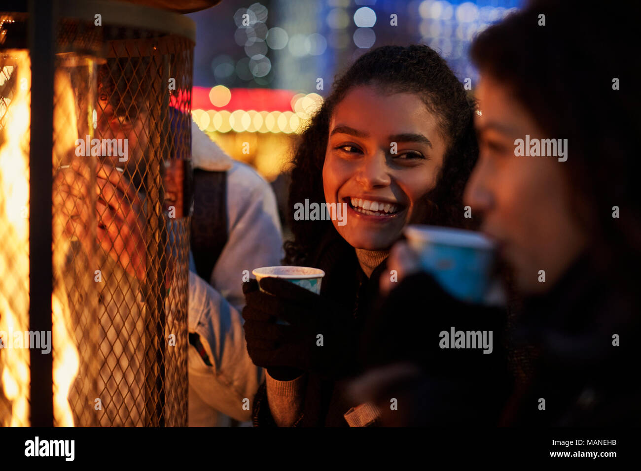 Weibliche Freunde trinken Glühwein am Weihnachtsmarkt Stockfoto